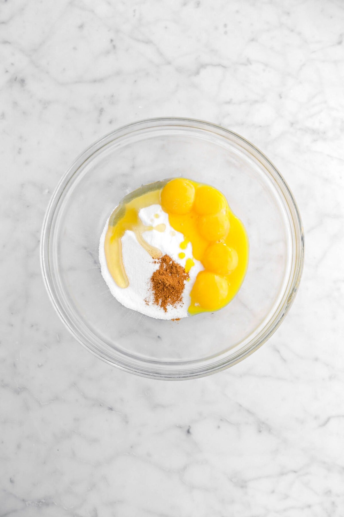 sugar, agave, ground cinnamon, and egg yolks in glass bowl.
