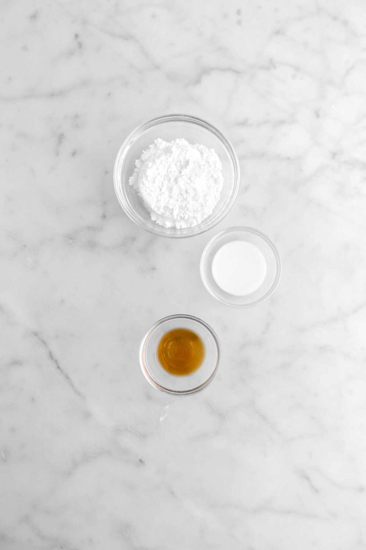 powdered sugar, milk, and vanilla on marble surface.