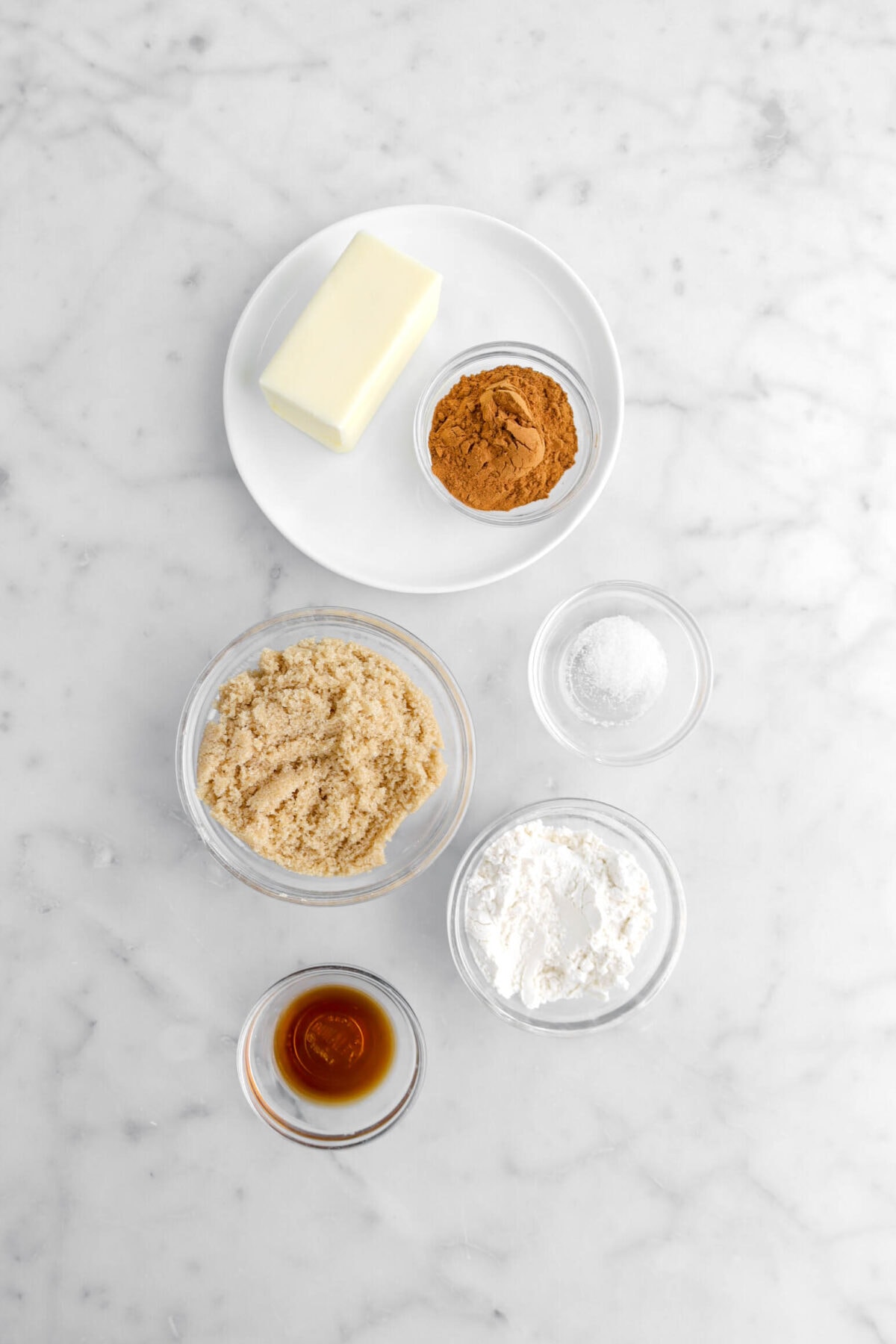 butter, cinnamon, salt, brown sugar, flour, and vanilla on marble surface.