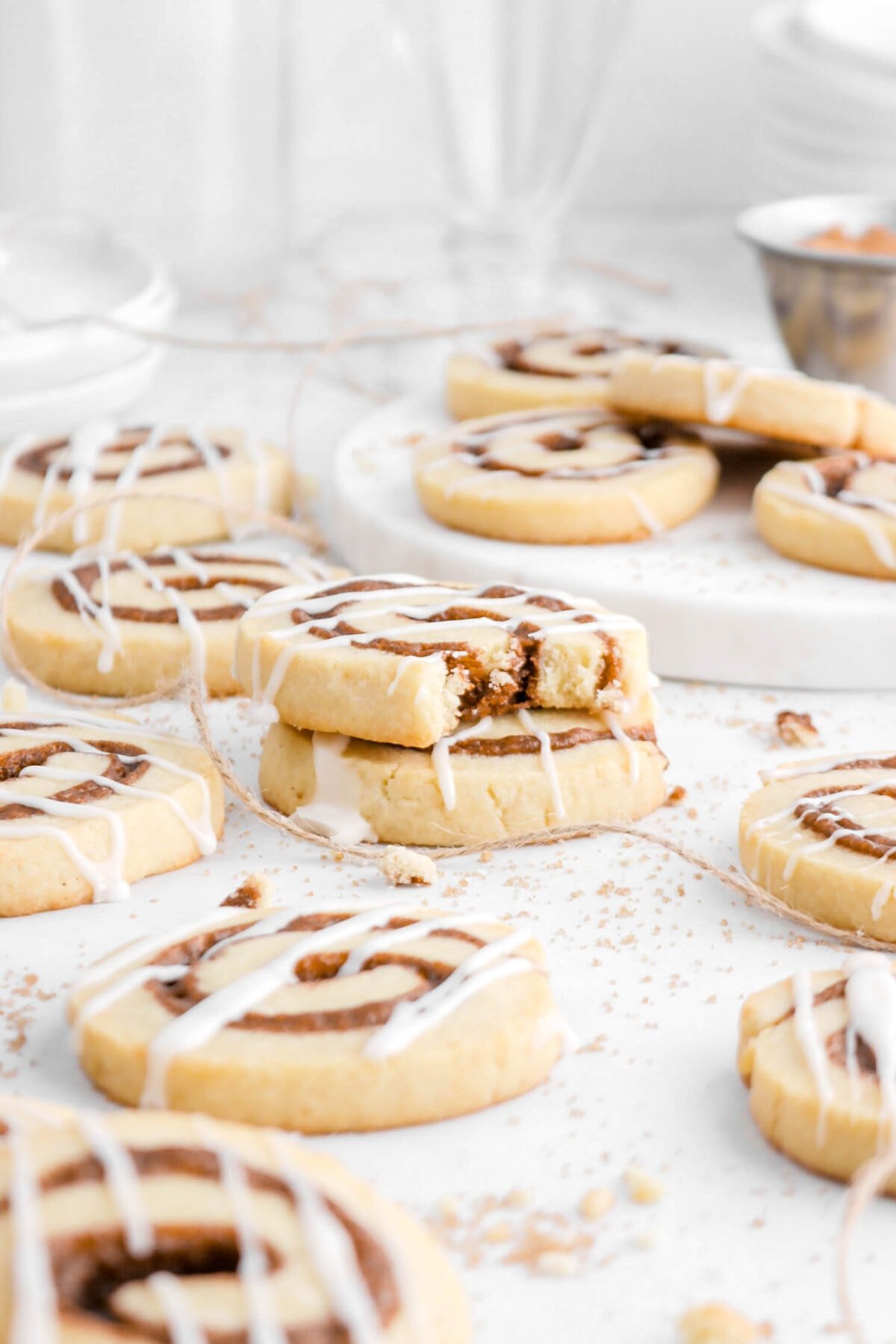 front shot of two stacked cinnamon roll cookies with more around on parchment paper.
