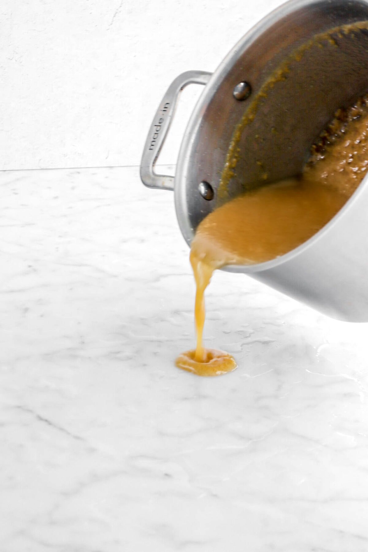 caramel being poured onto wet marble counter.