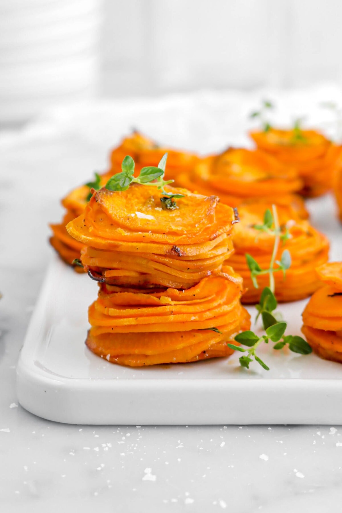 close up of two sweet potato stacks stacked on top of each other on white tray with more behind.