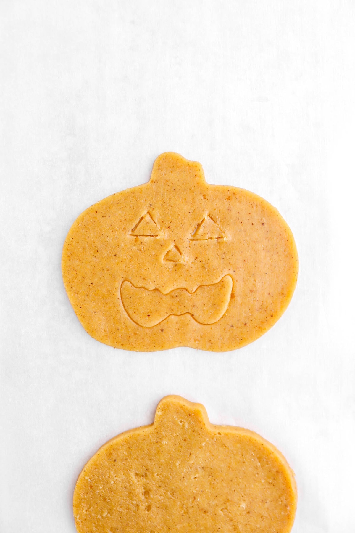 face cut into pumpkin shaped cookie dough.