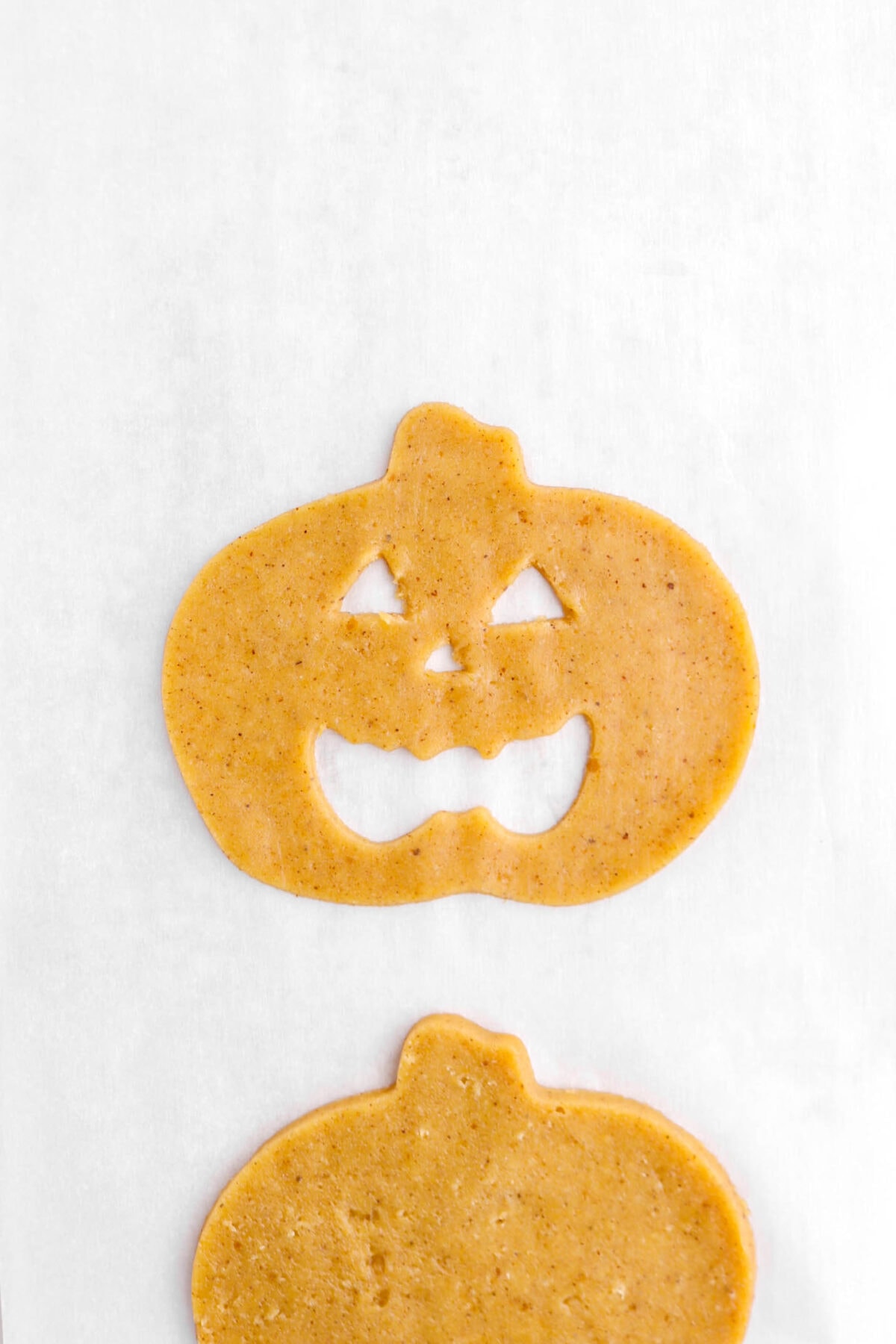 unbaked jack o'lantern cookie on parchment paper.