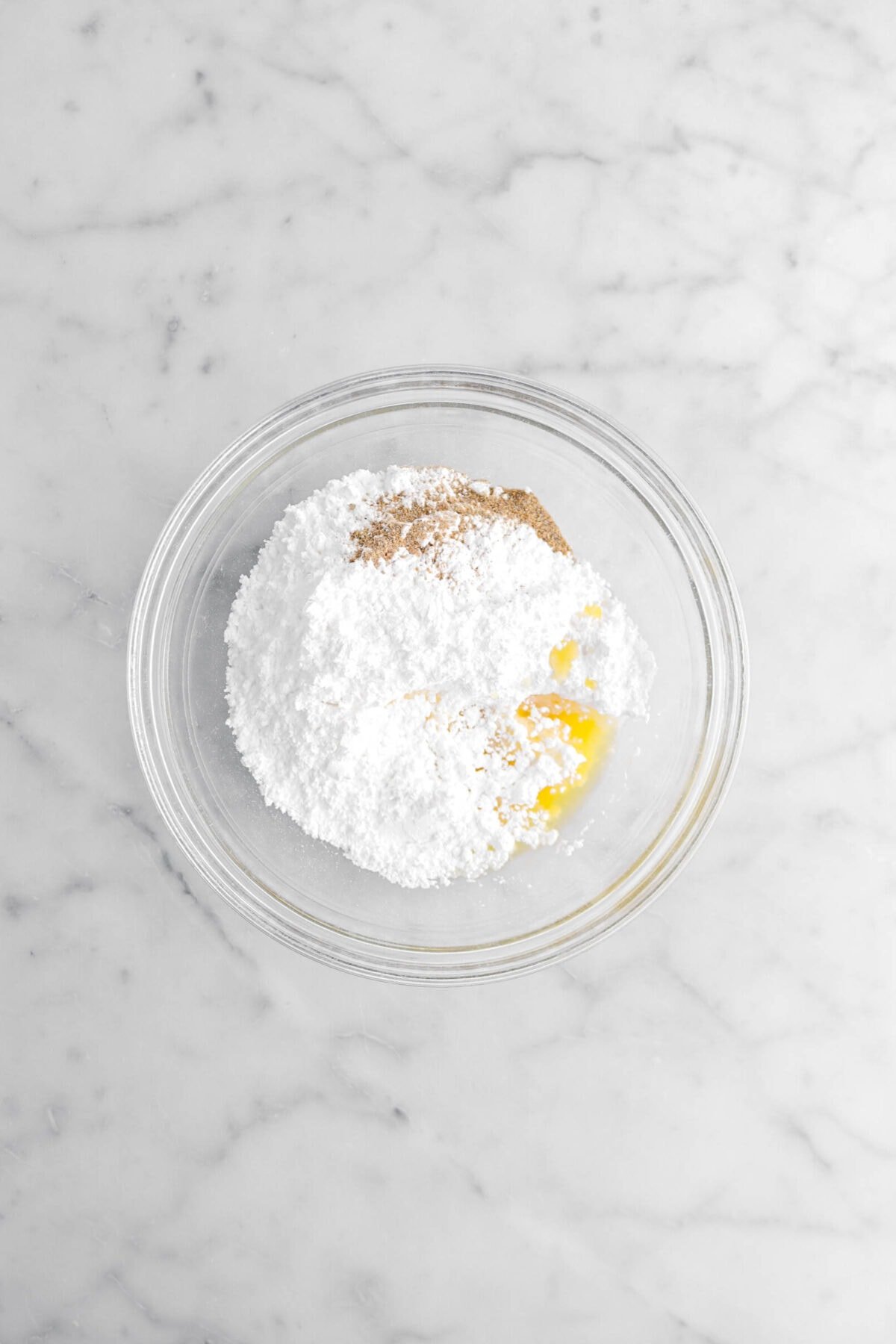 powdered sugar, ground cardamom, and orange juice in glass bowl.
