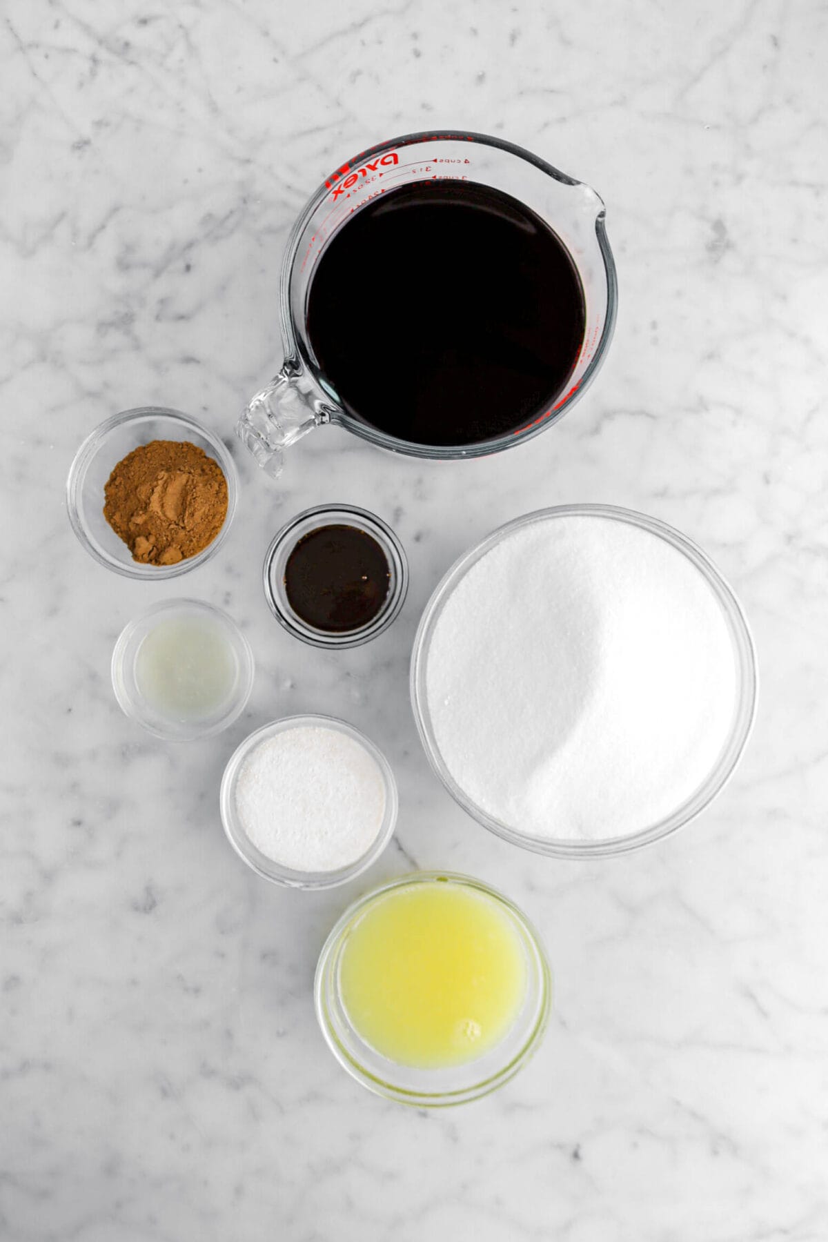wine, ground spices, molasses, lemon juice, pectin, sugar, and orange juice on marble surface.