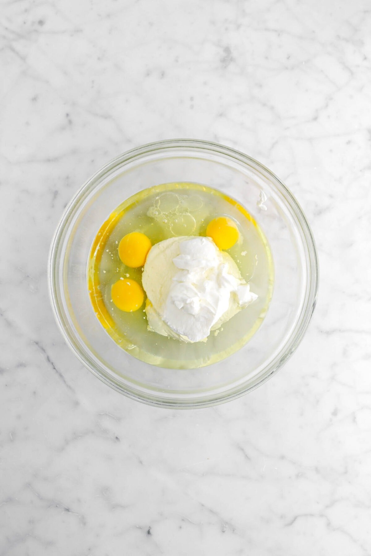 vegetable oil, eggs, lemon juice, and yogurt in glass bowl.