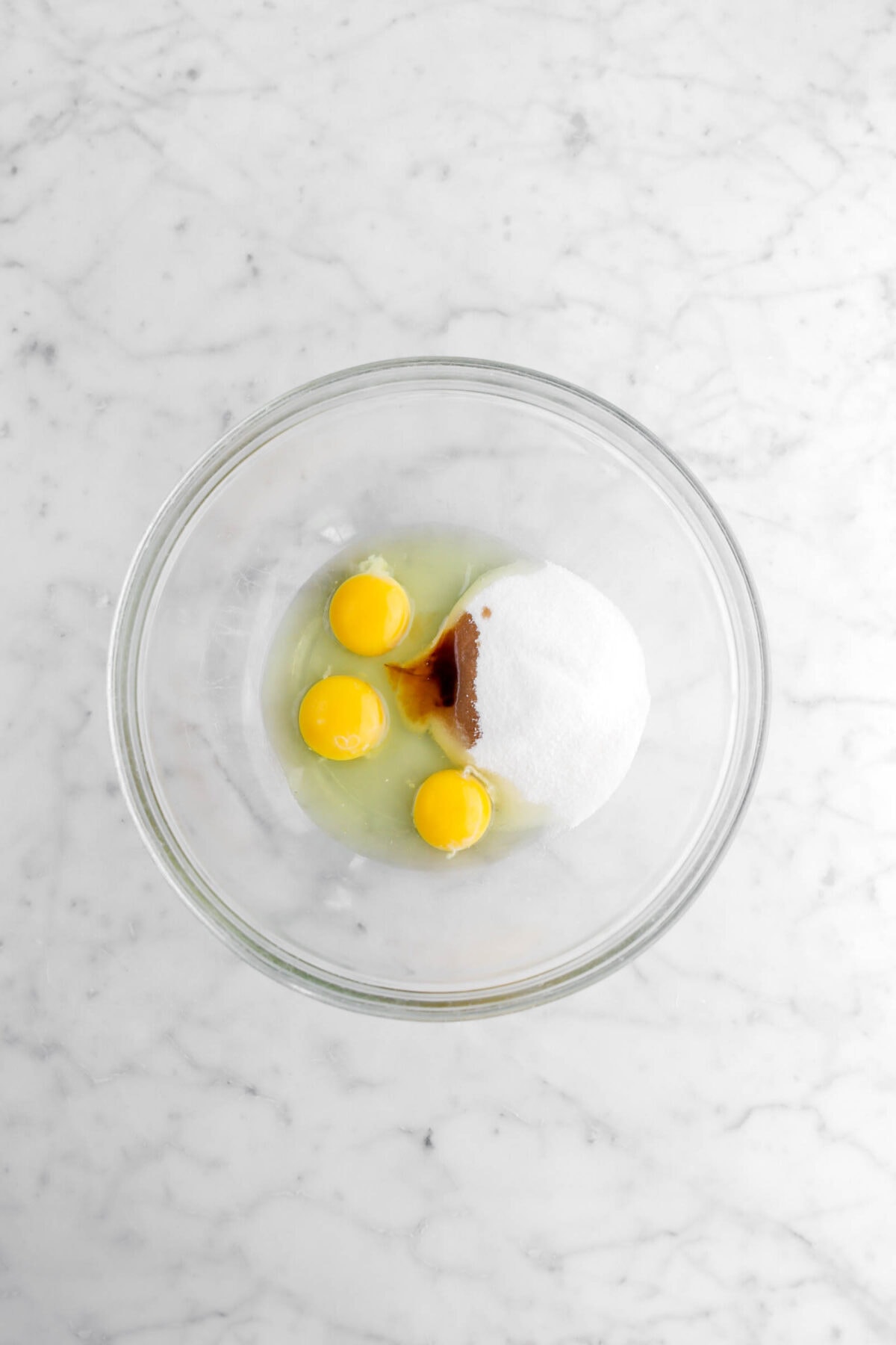 eggs, vanilla, and sugar in glass bowl.