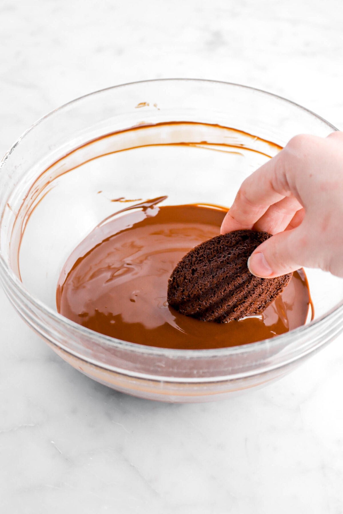 madeleine being dipped in melted chocolate.