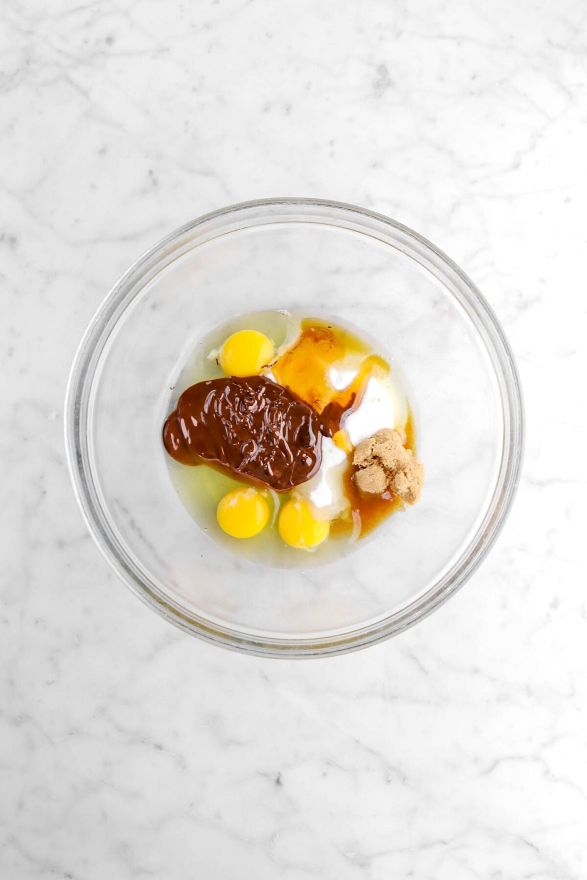 melted chocolate, honey, eggs, sugar, and brown sugar in glass bowl.