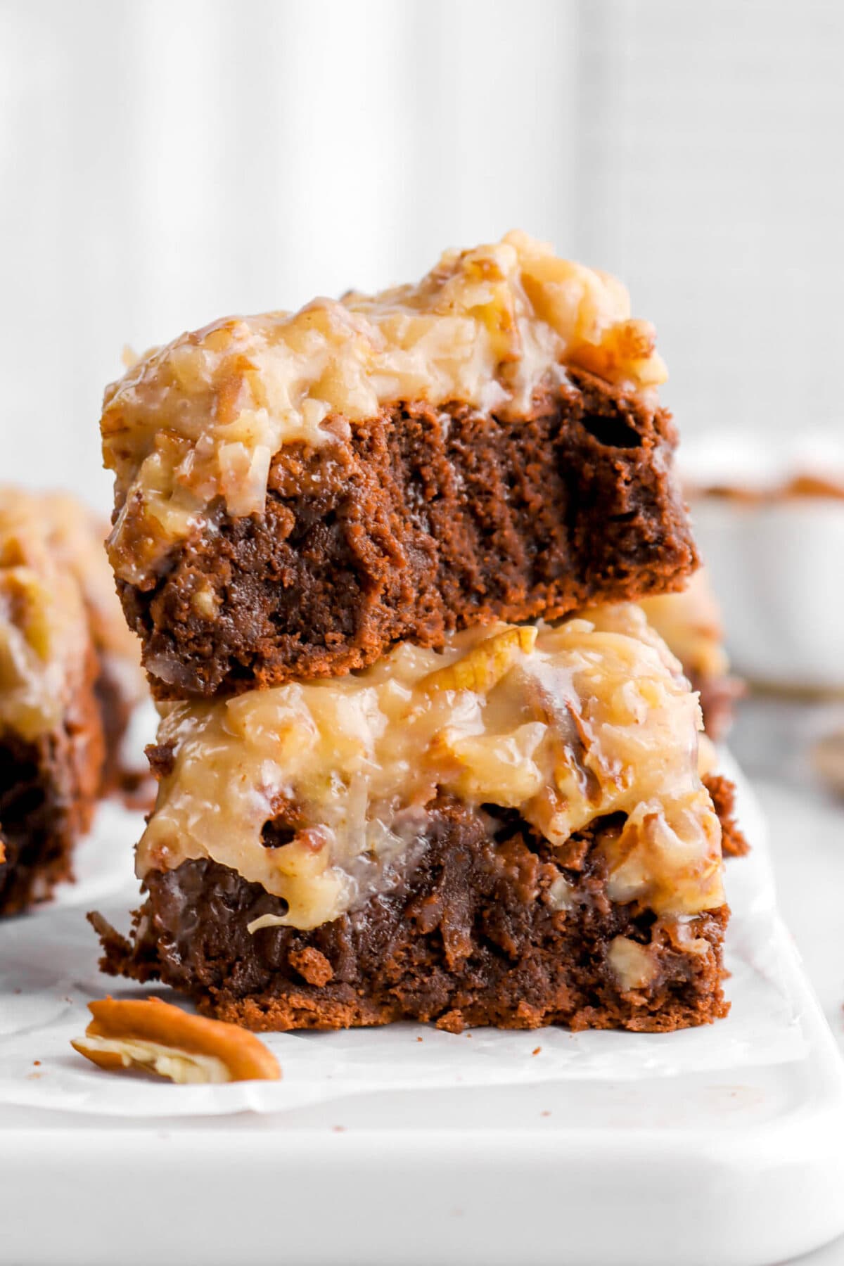close up of two stacked german chocolate brownies with bite taken out of top brownie.