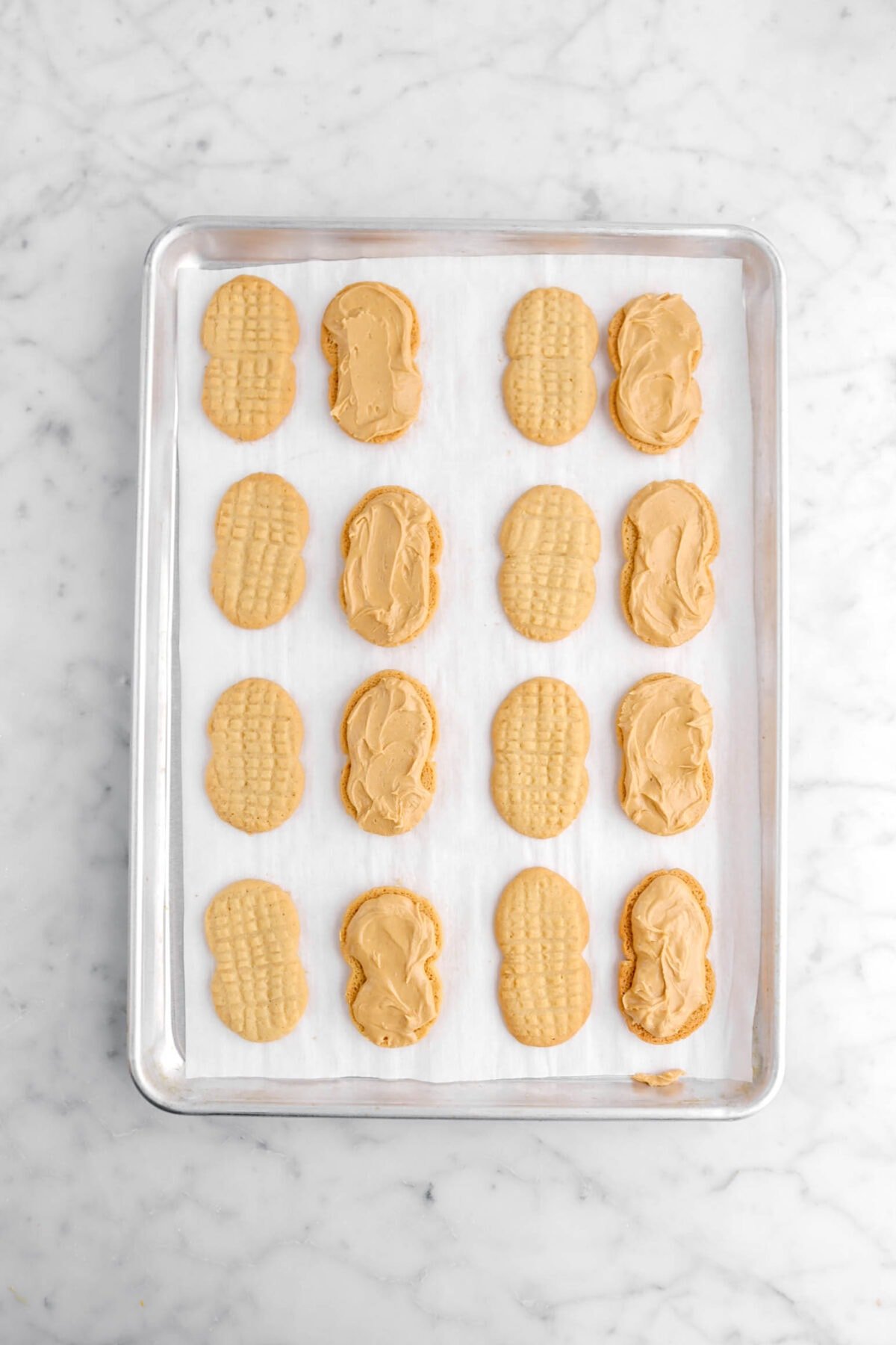 peanut butter filling added onto half of the cookies on a lined sheet pan.