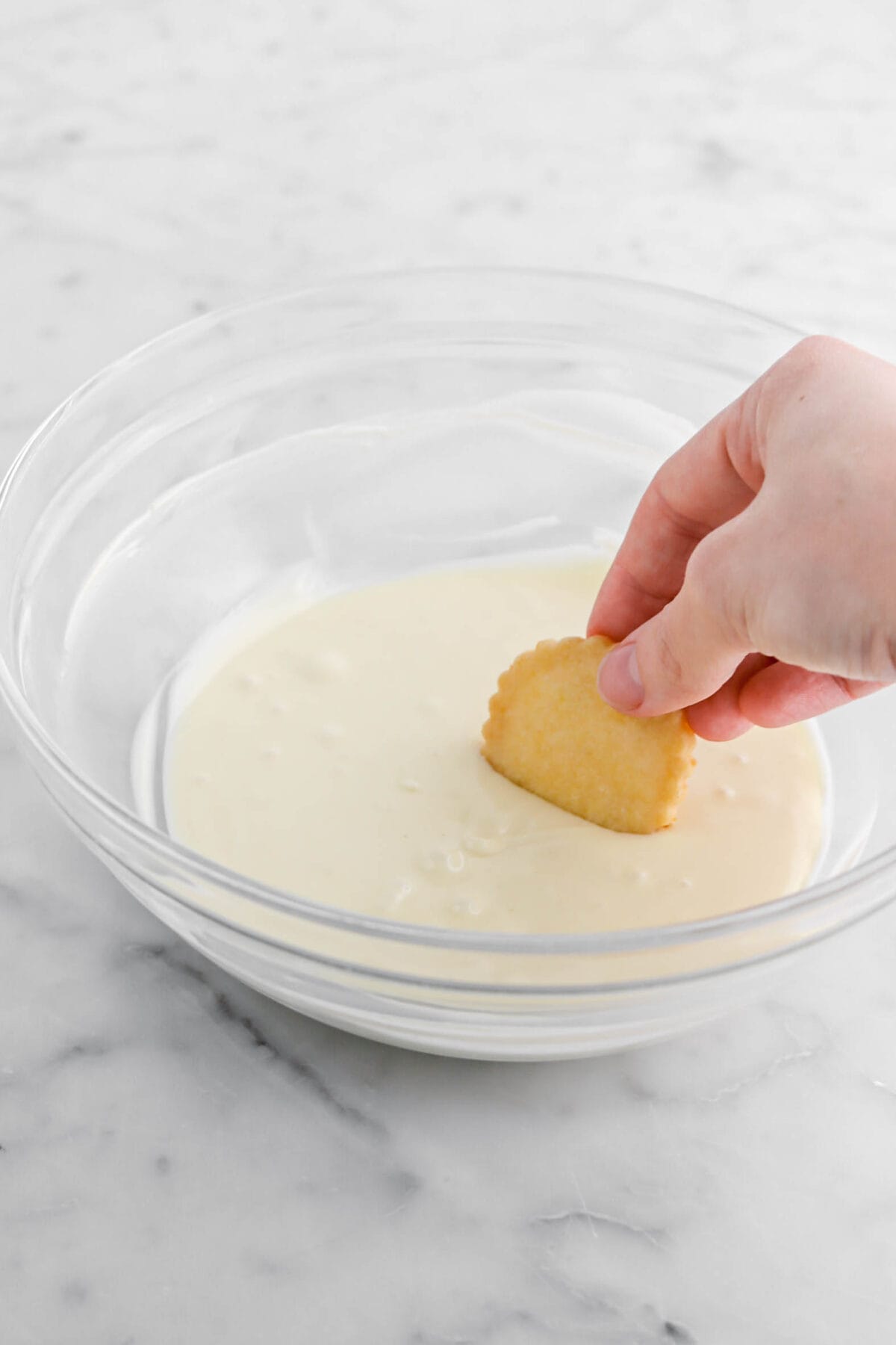 cookie being dipped in melted white chocolate.