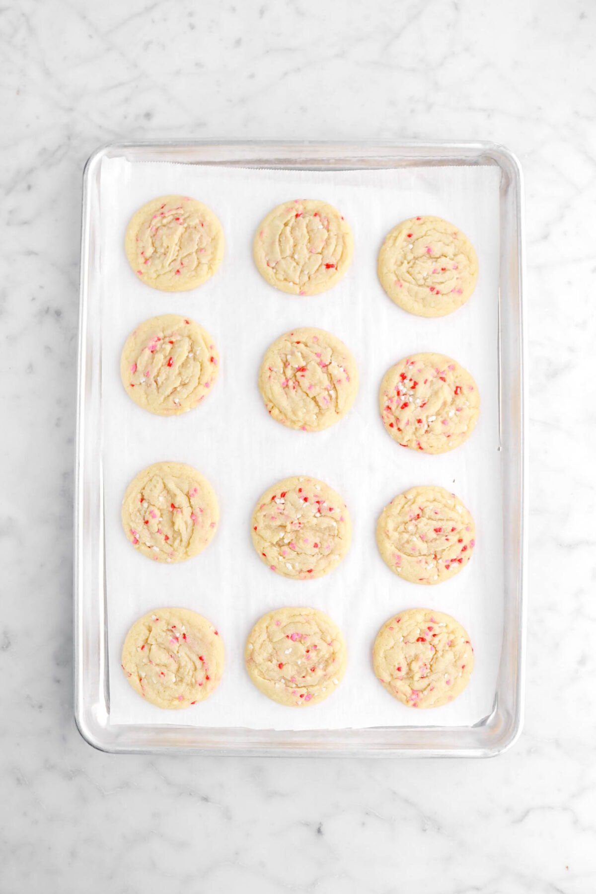 twelve baked cookies on lined sheet pan.