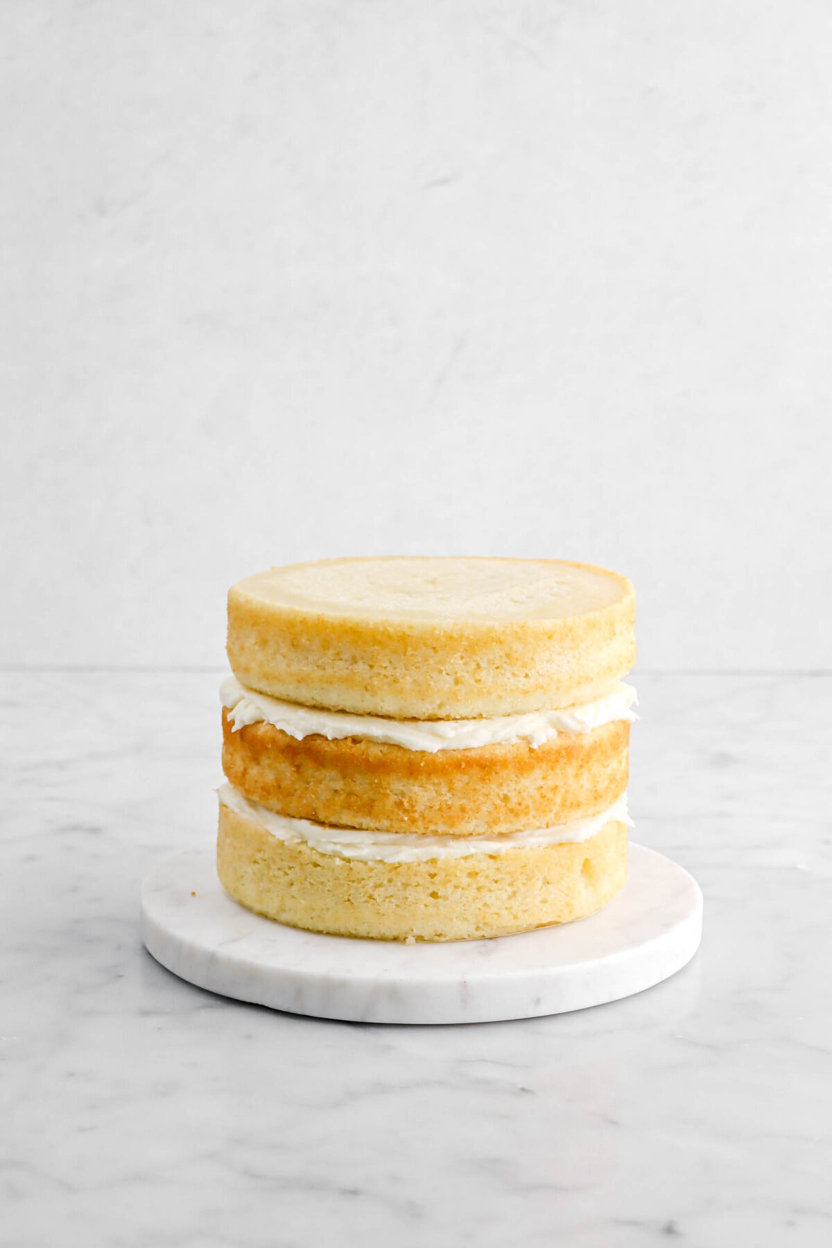 unfrosted three layer cake on marble stand.