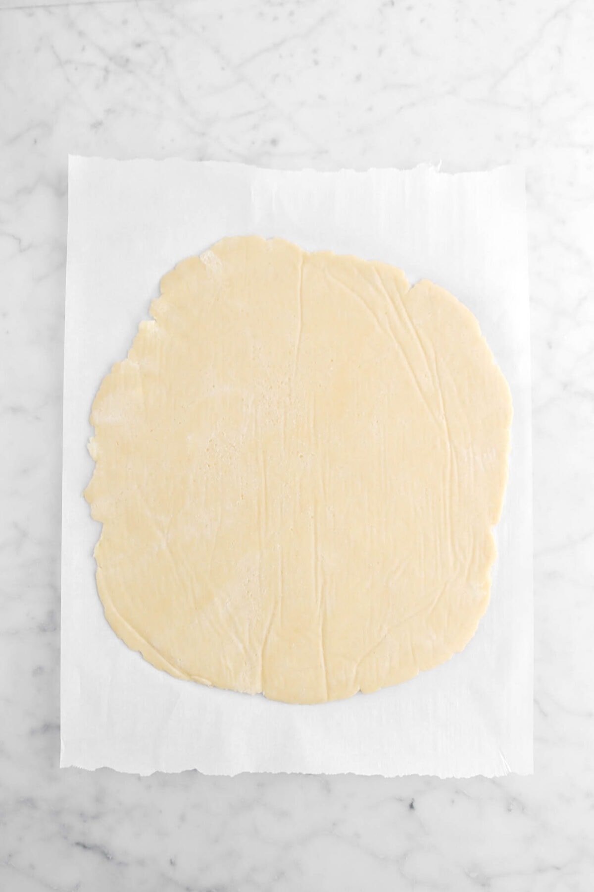 pie dough rolled out on parchment paper.