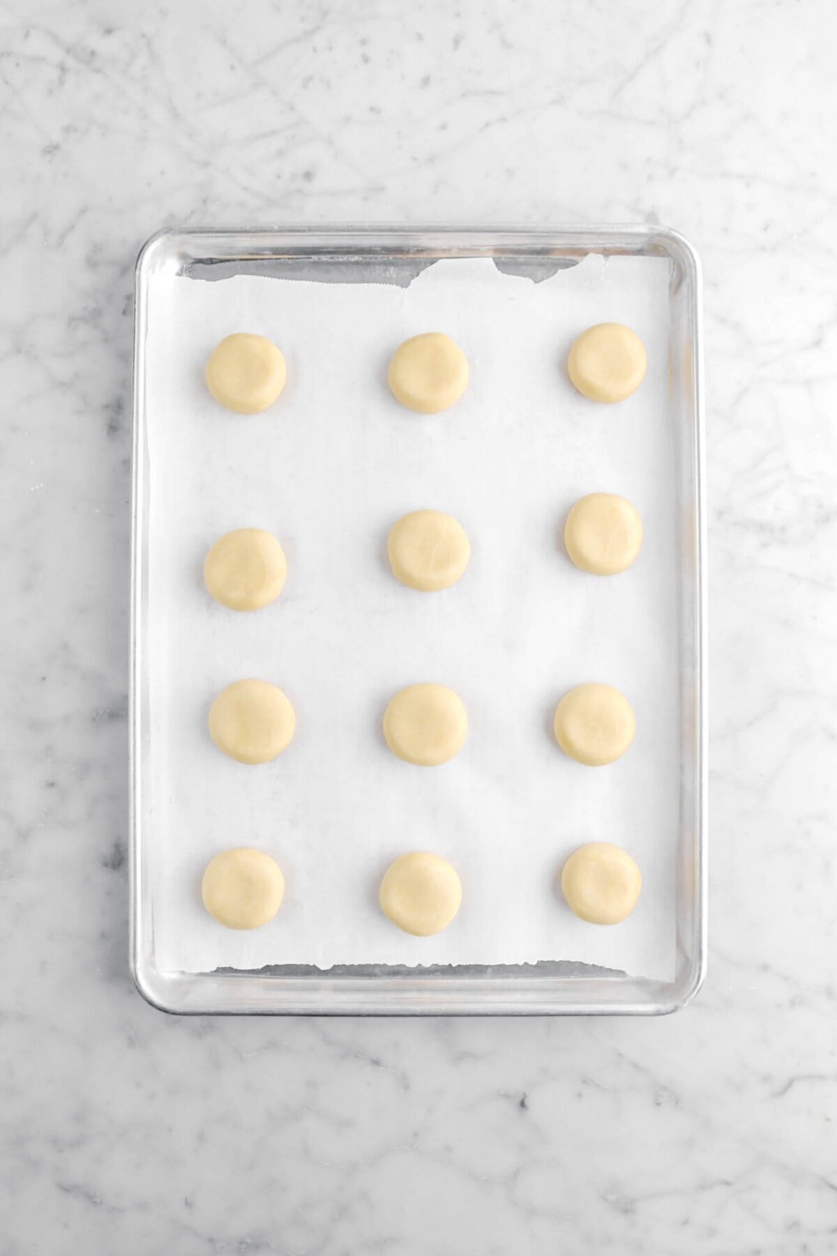 cookie dough balls flattened slightly on lined sheet pan.