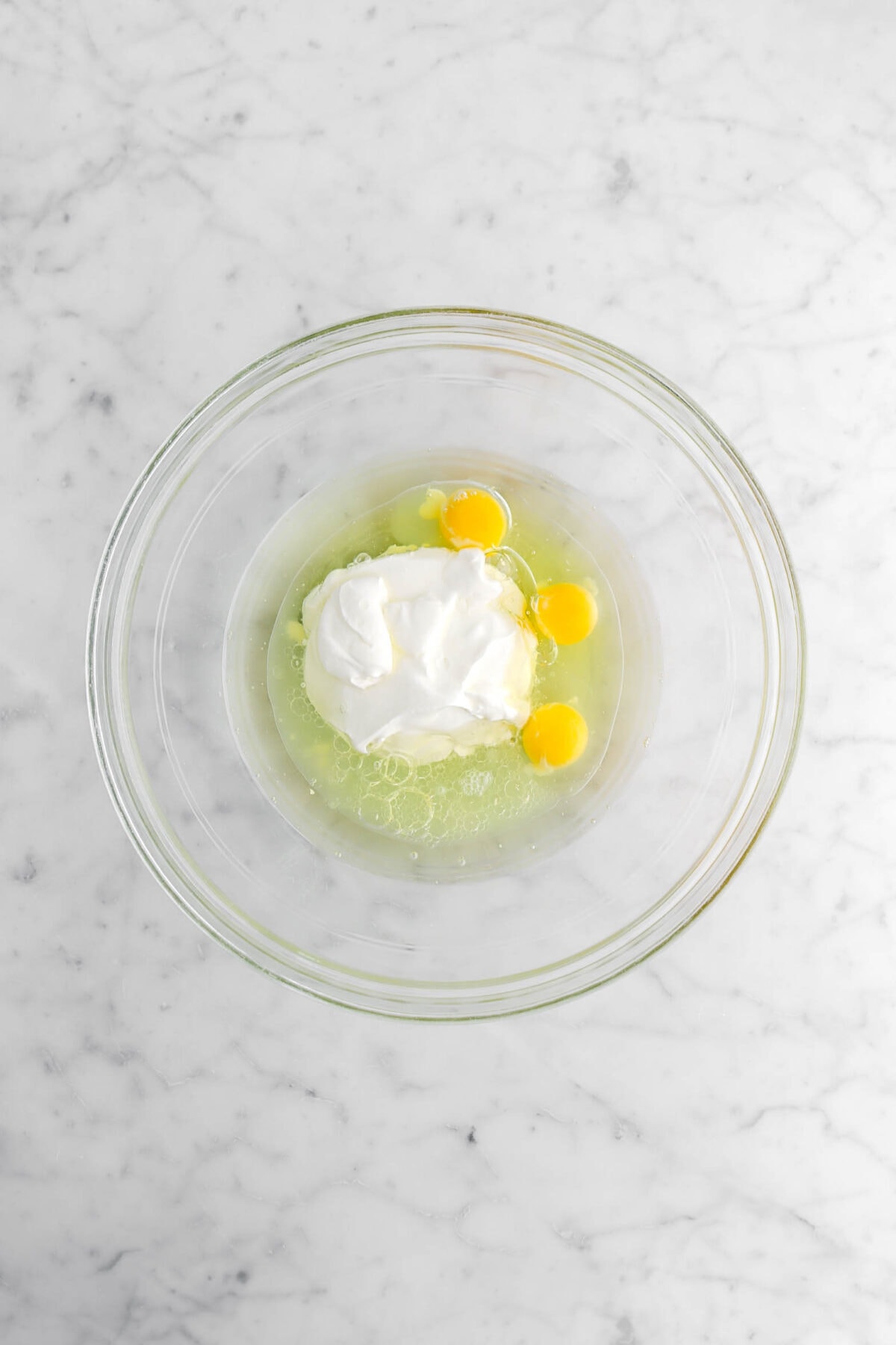 oil, eggs, lime juice, and sour cream in glass bowl.