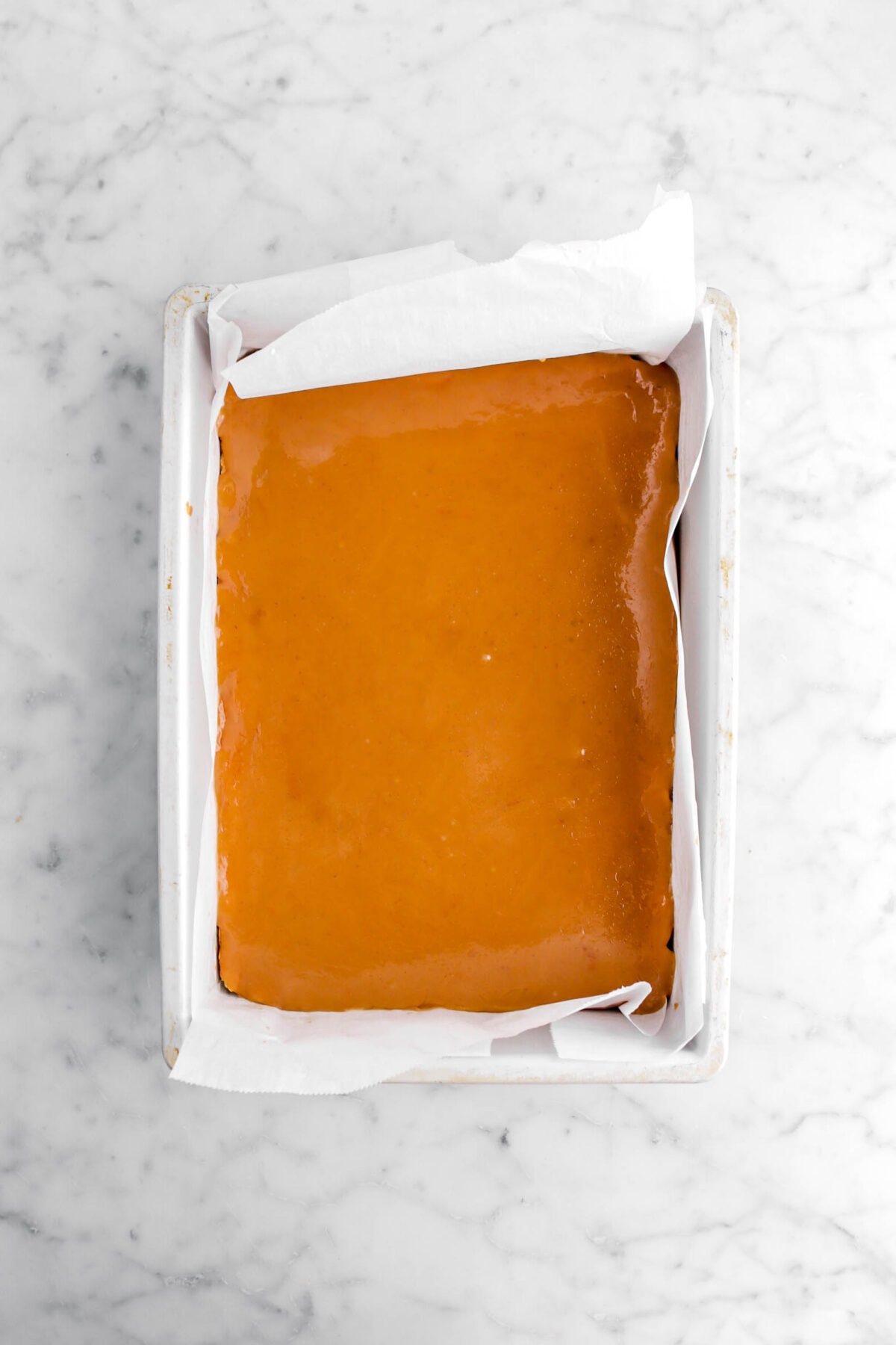 caramel on top of shortbread in lined cake pan.