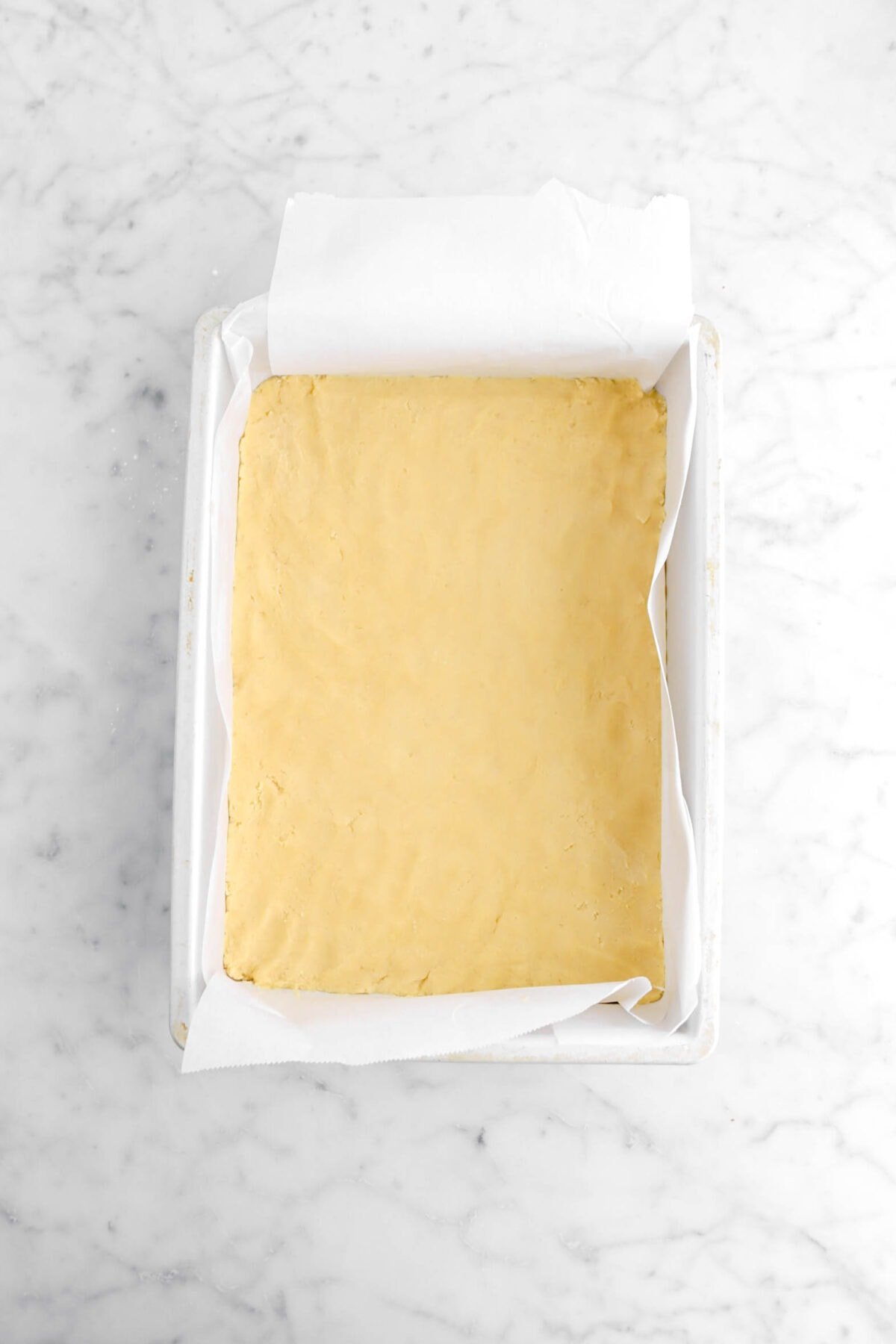 shortbread cookie dough pressed into lined cake pan.