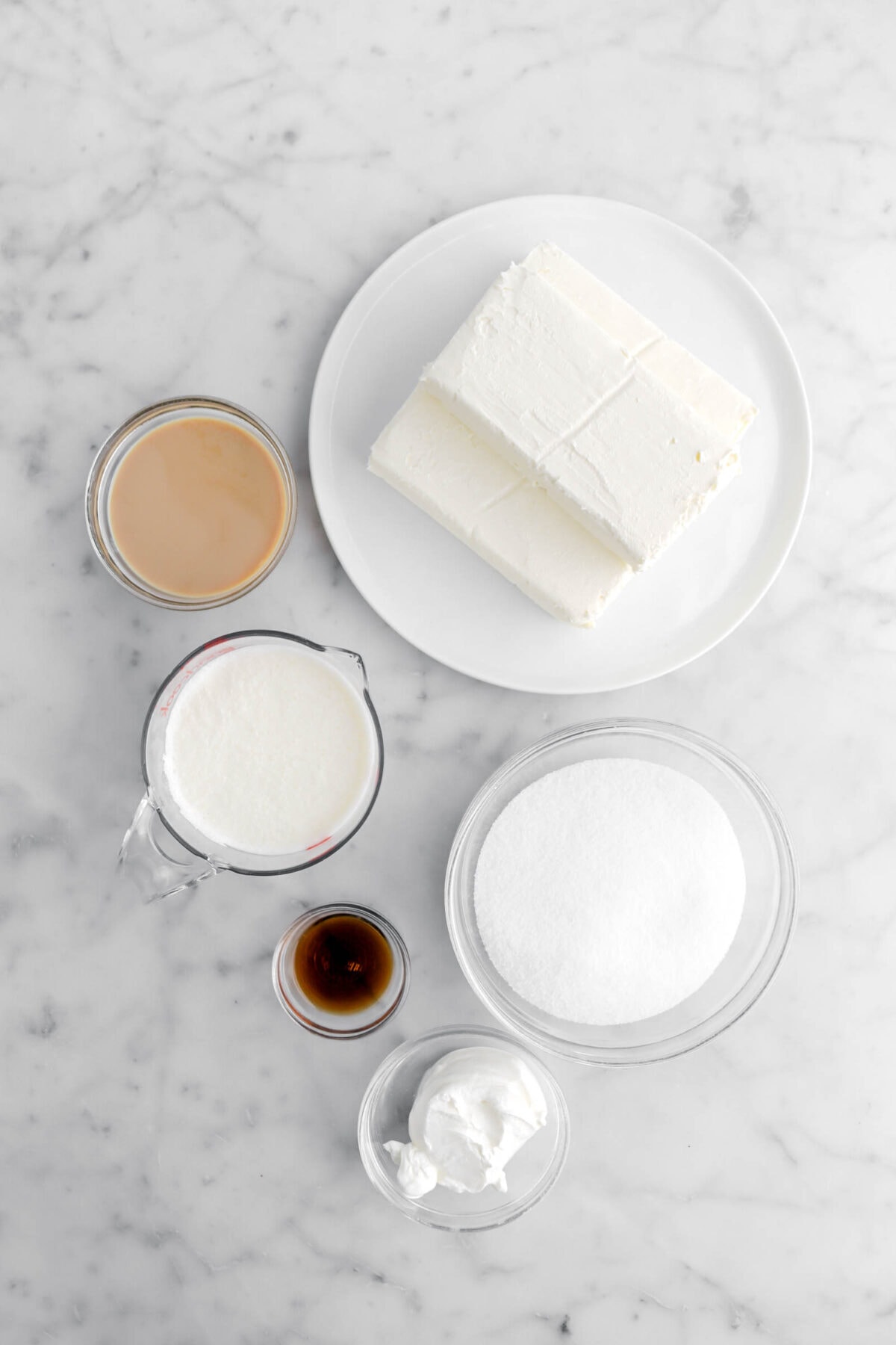 cream cheese, irish cream heavy cream, sugar, vanilla, and sour cream on marble surface.