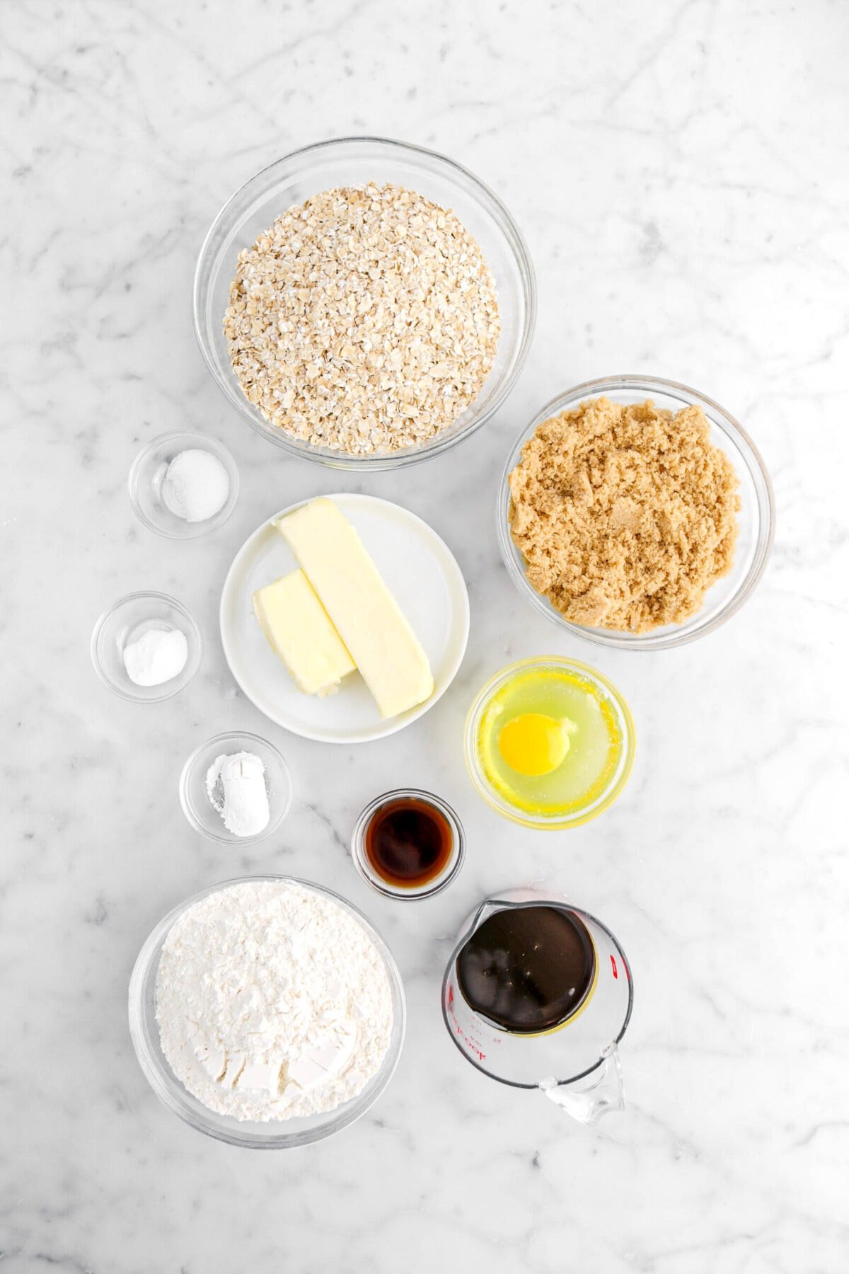 oats, salt, butter, baking soda, baking powder, brown sugar, egg, vanilla, flour, and molasses on marble surface.