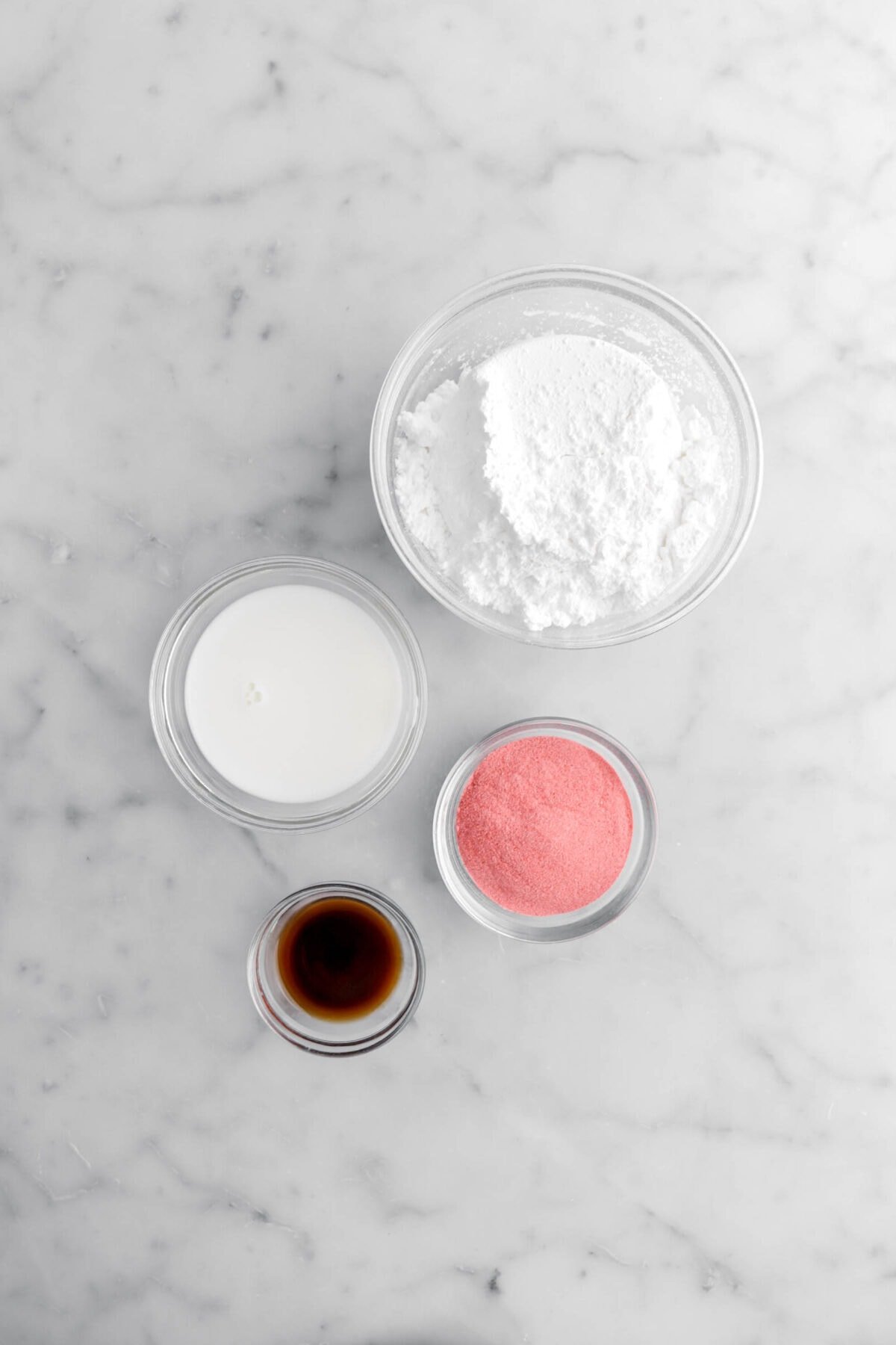 powdered sugar, milk strawberry powder, and vanilla on marble surface.