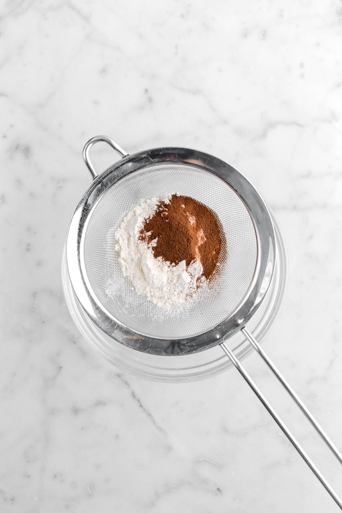 flour and espresso powder in sieve over glass bowl.