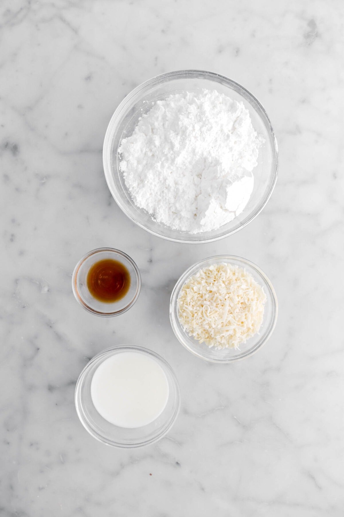 powdered sugar, vanilla, shredded coconut, and vanilla on marble surface.