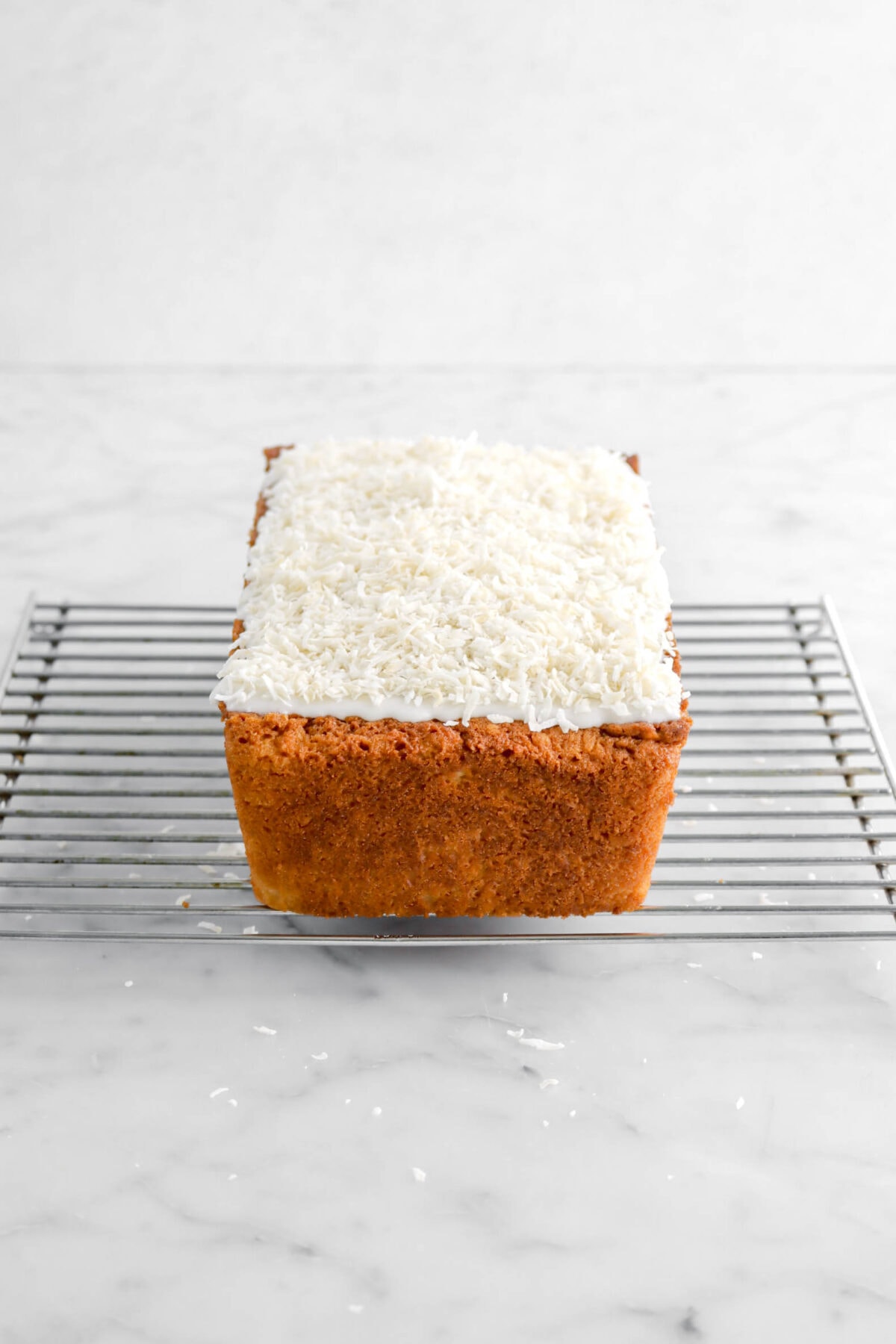 shredded coconut added on top of icing on loaf cake.