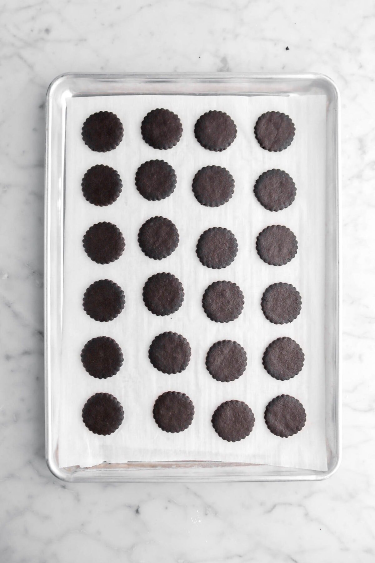 twenty four baked chocolate cookies on lined sheet pan.