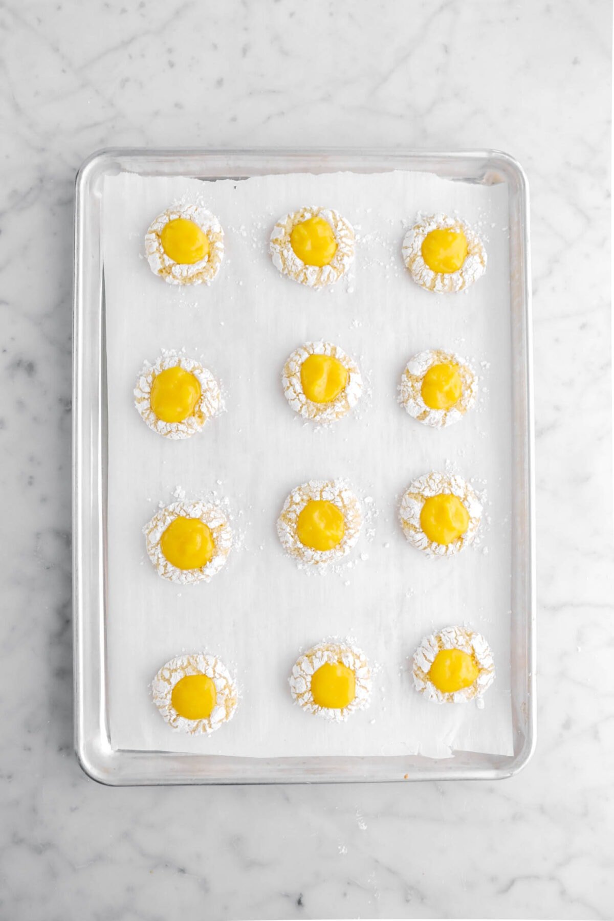 lemon curd filled crinkle cookies on lined sheet pan.