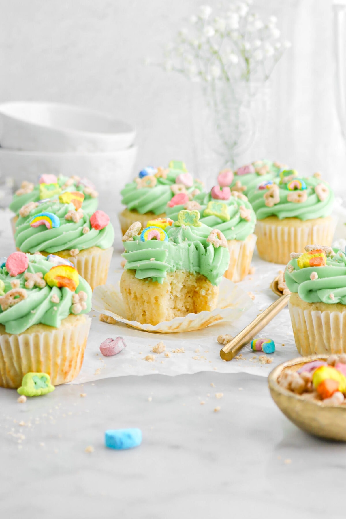 nine lucky charms cupcakes on parchment paper with bite missing from middle cupcake.