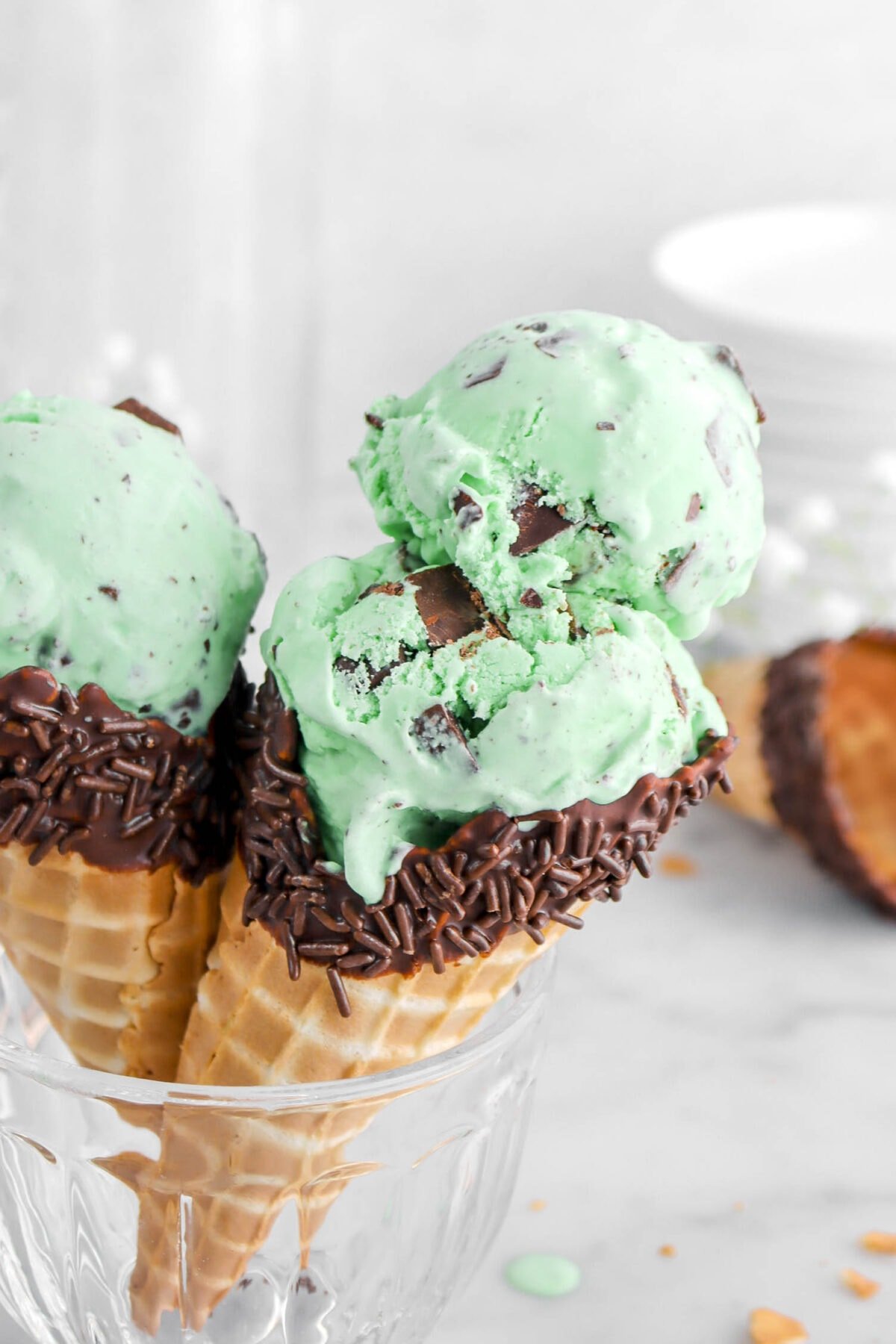 close up of two scoops of mint chip ice cream in chocolate dipped cone.
