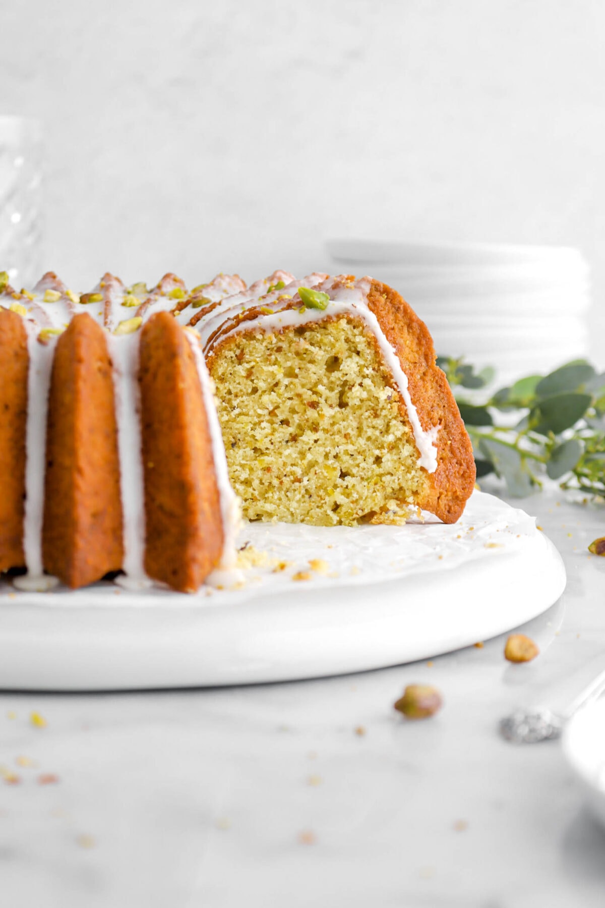 close up of sliced pistachio bundt cake on upside down white plate.