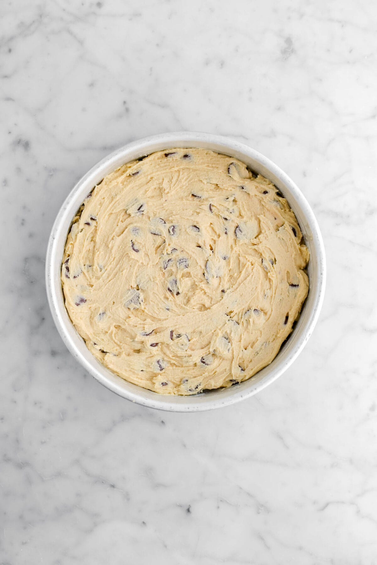 chocolate chip cookie dough spread in round cake pan.