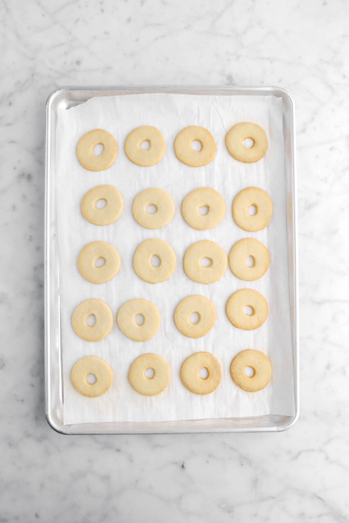 baked ring shaped shortbread cookies on lined sheet pan.