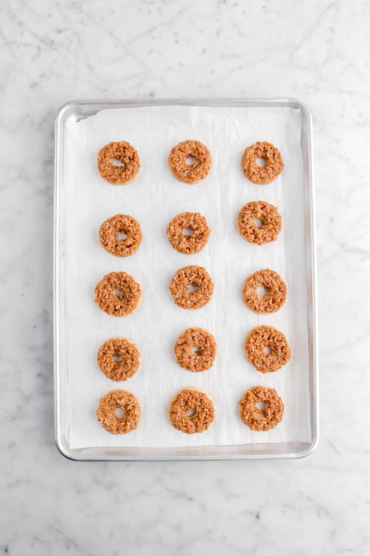 coconut caramel on shortbread cookies on lined sheet pan.