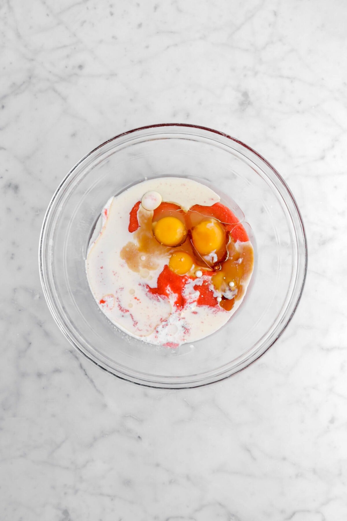 eggs, strawberry purée, oil, and milk in glass bowl.
