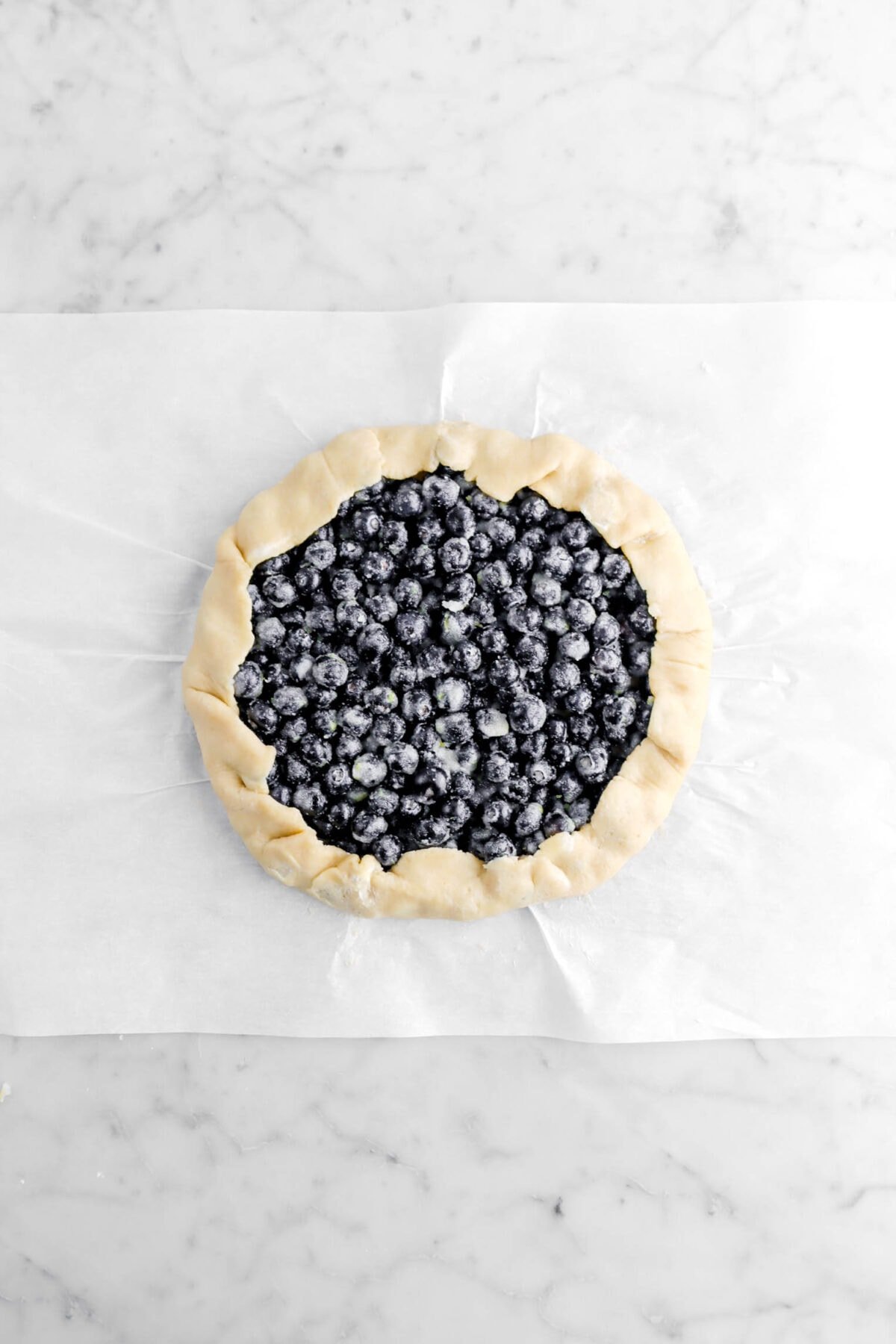 edges of pie crust folded up over blueberries.