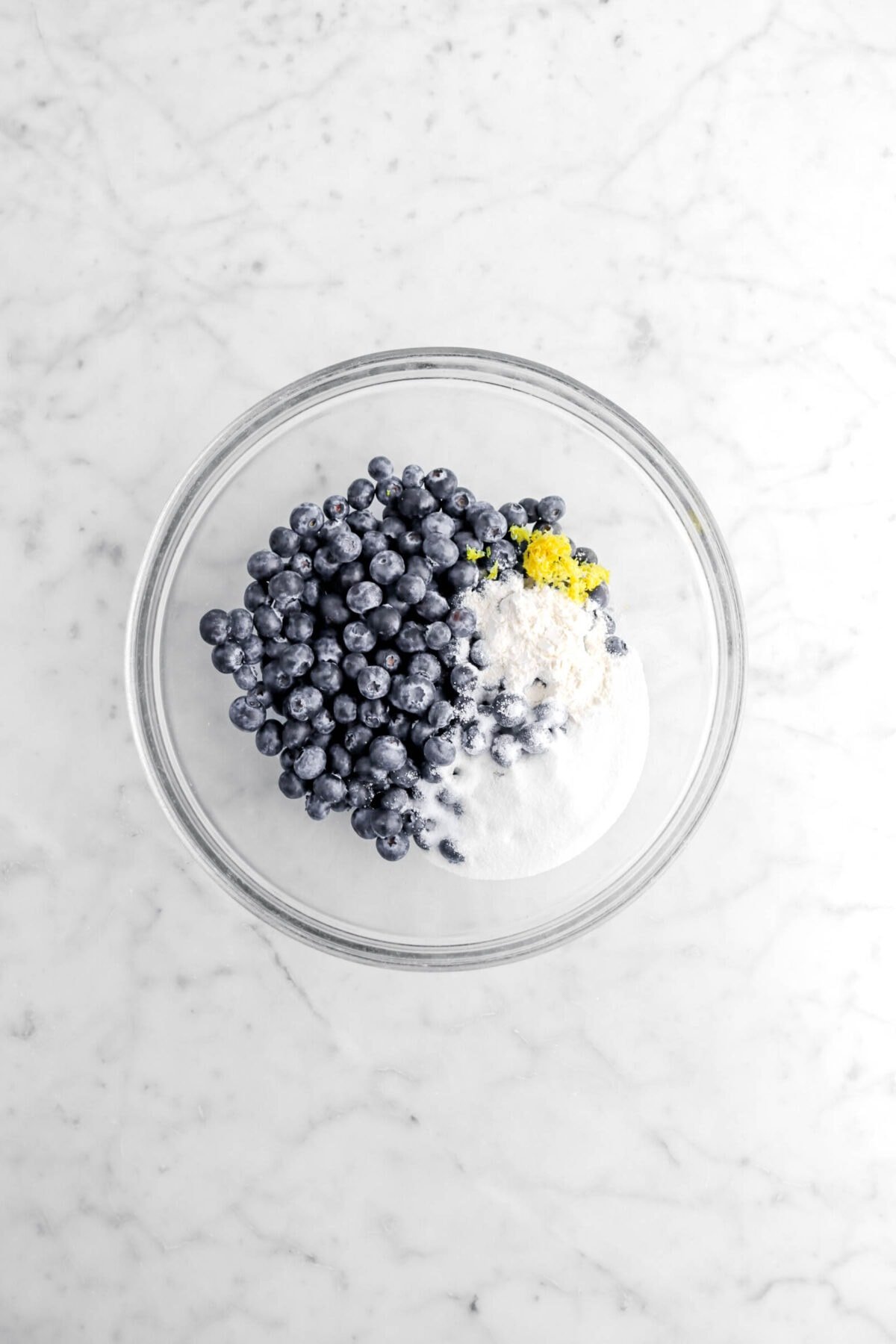 blueberries, sugar, flour, and lemon zest in glass bowl.