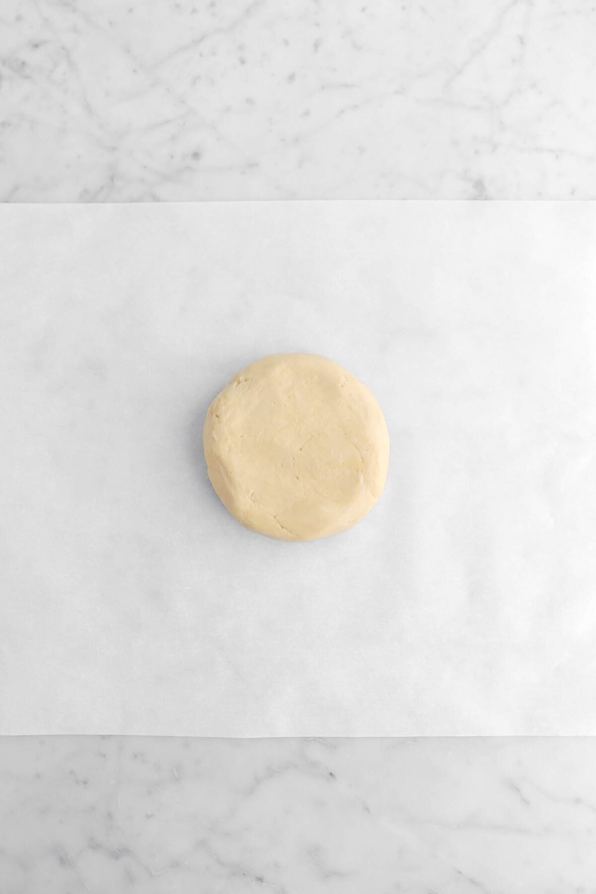 dough in a disc shape on parchment paper.