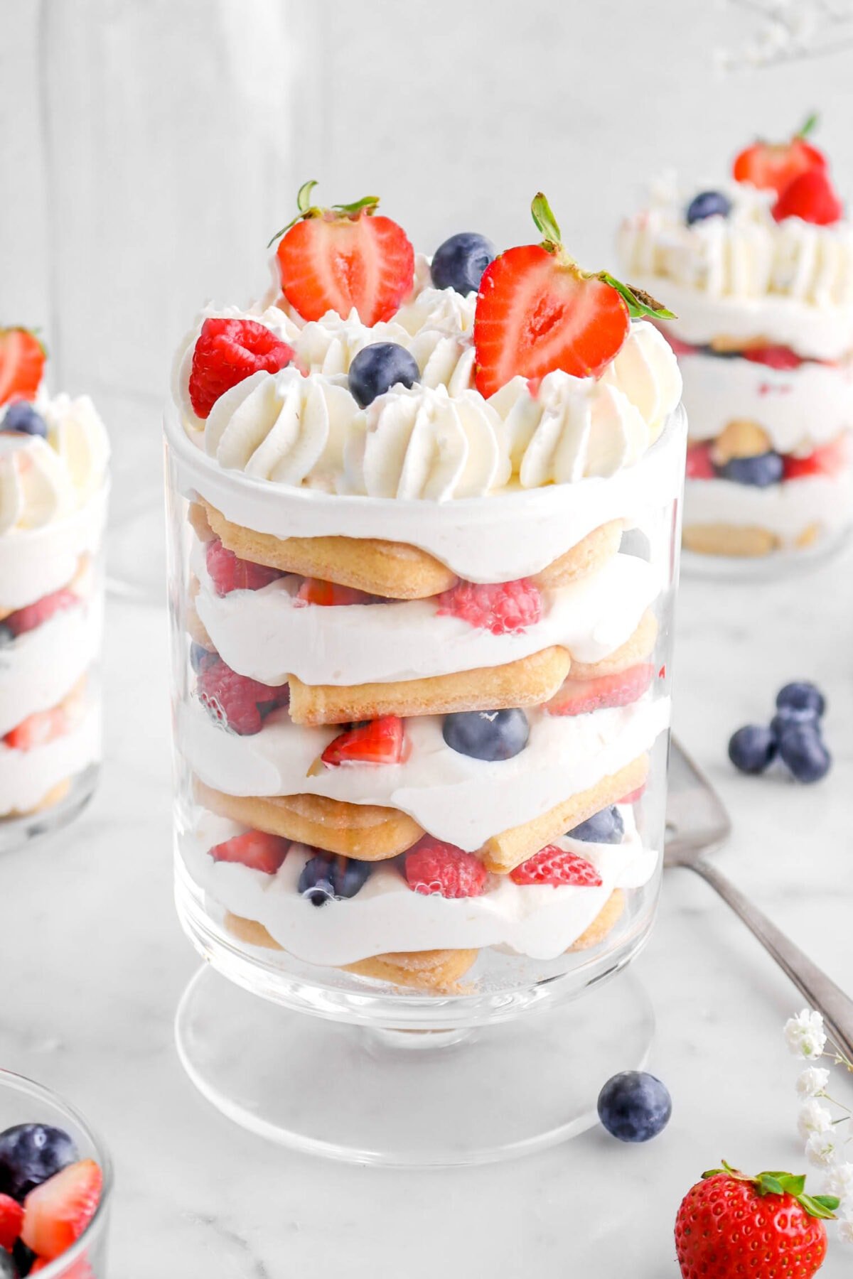 angled close up of berry trifle with two trifles behind and berries around.