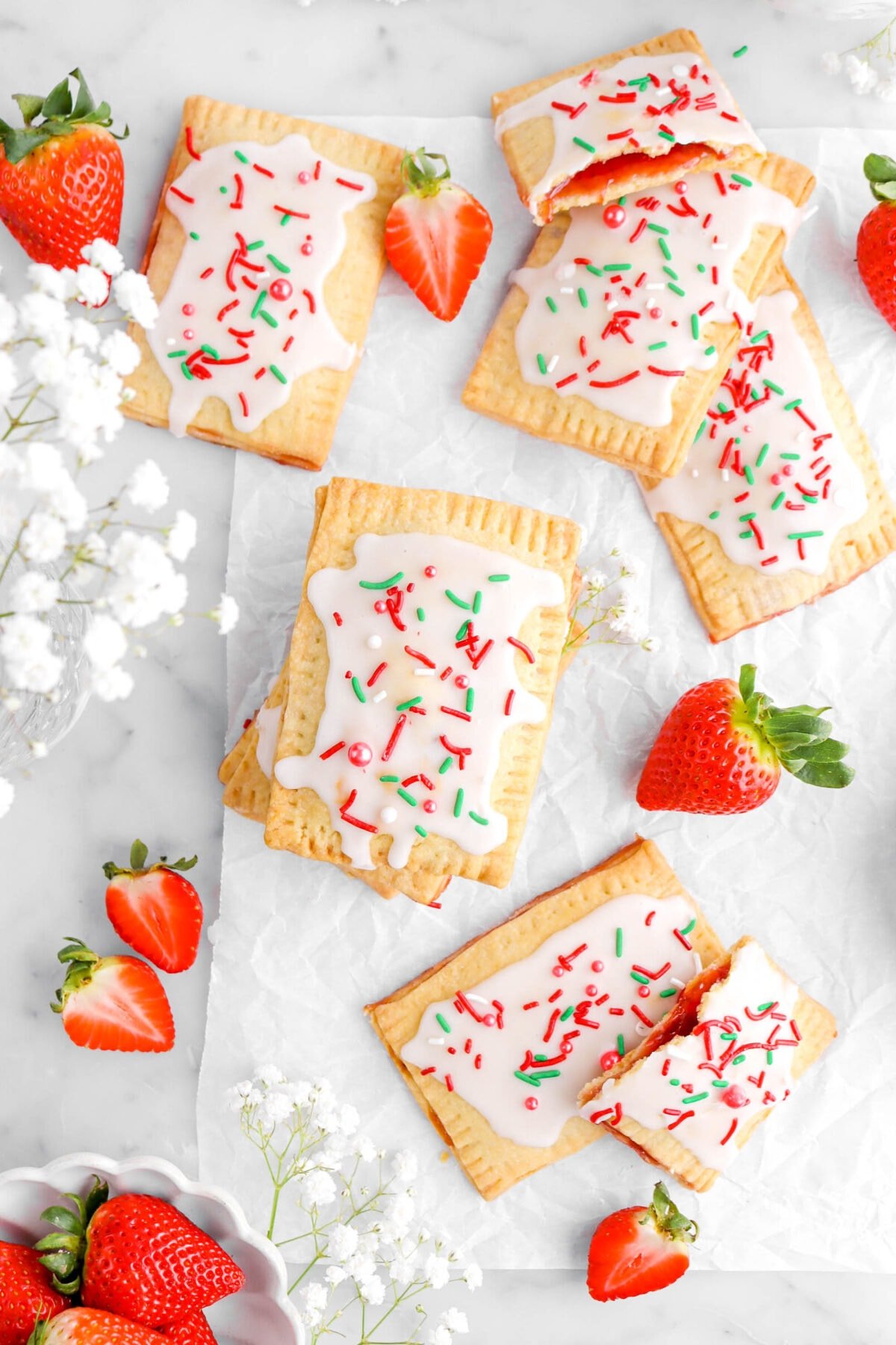 pop tarts on parchment paper with strawberries and white flowers around.