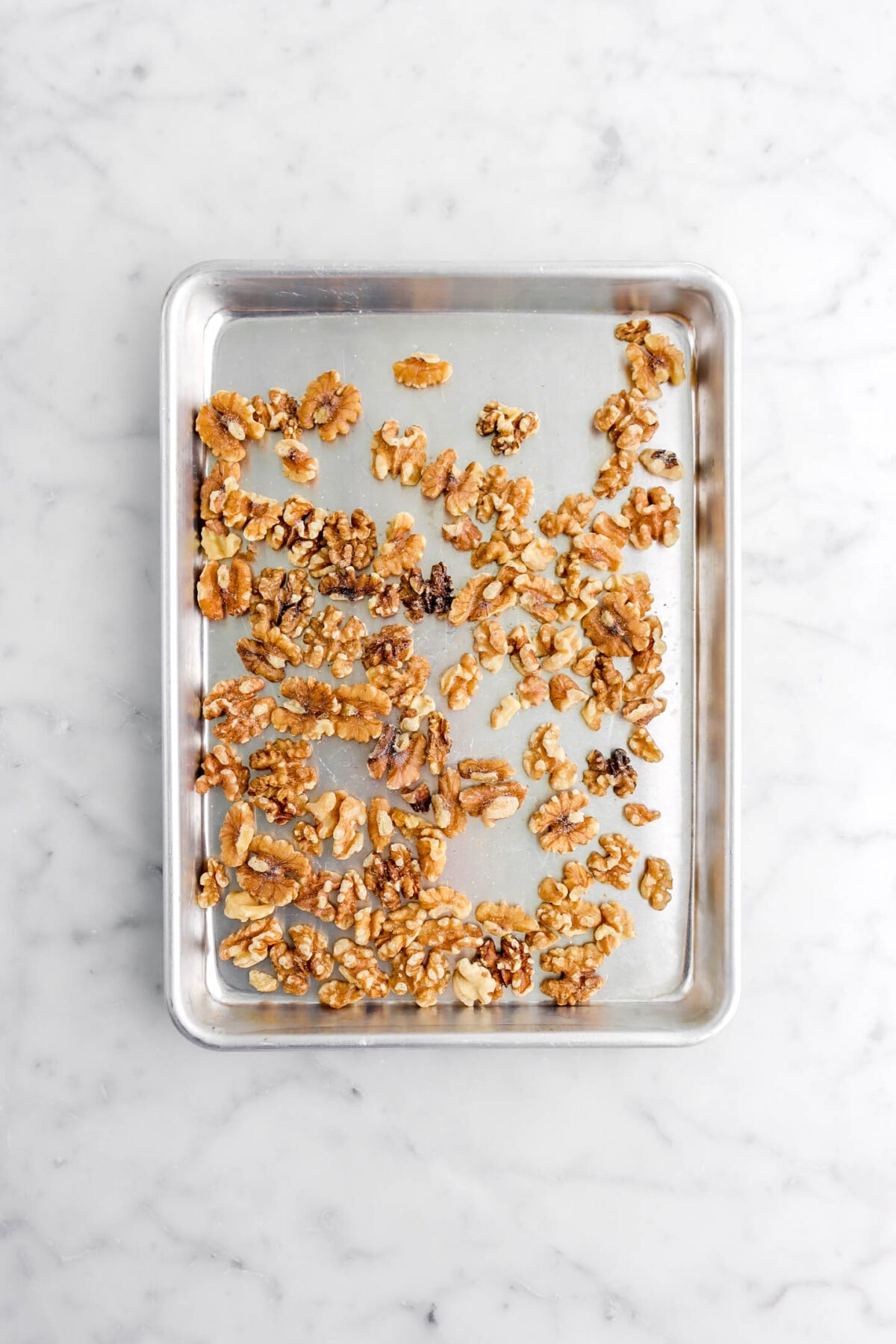 walnuts on small sheet pan on marble surface.