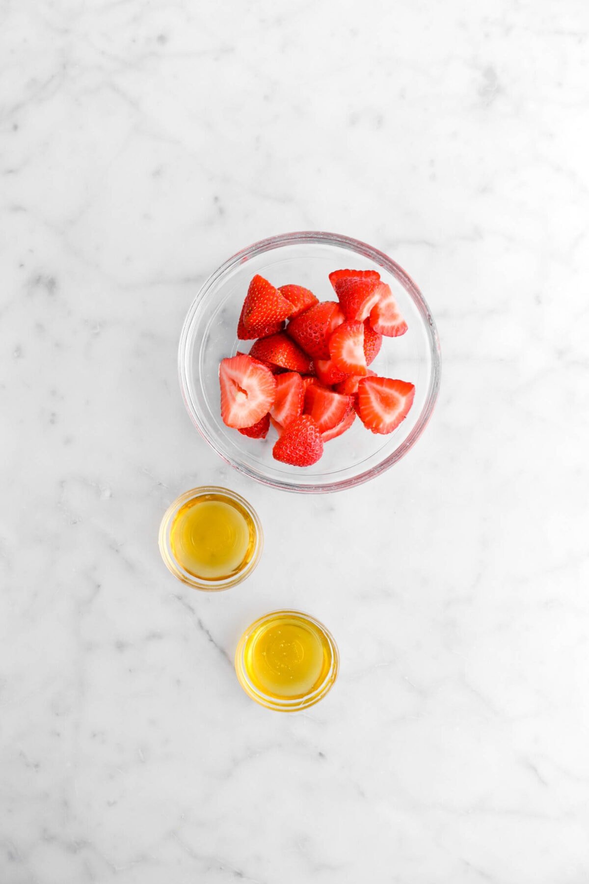 strawberries, honey, and orange liqueur on marble surface.