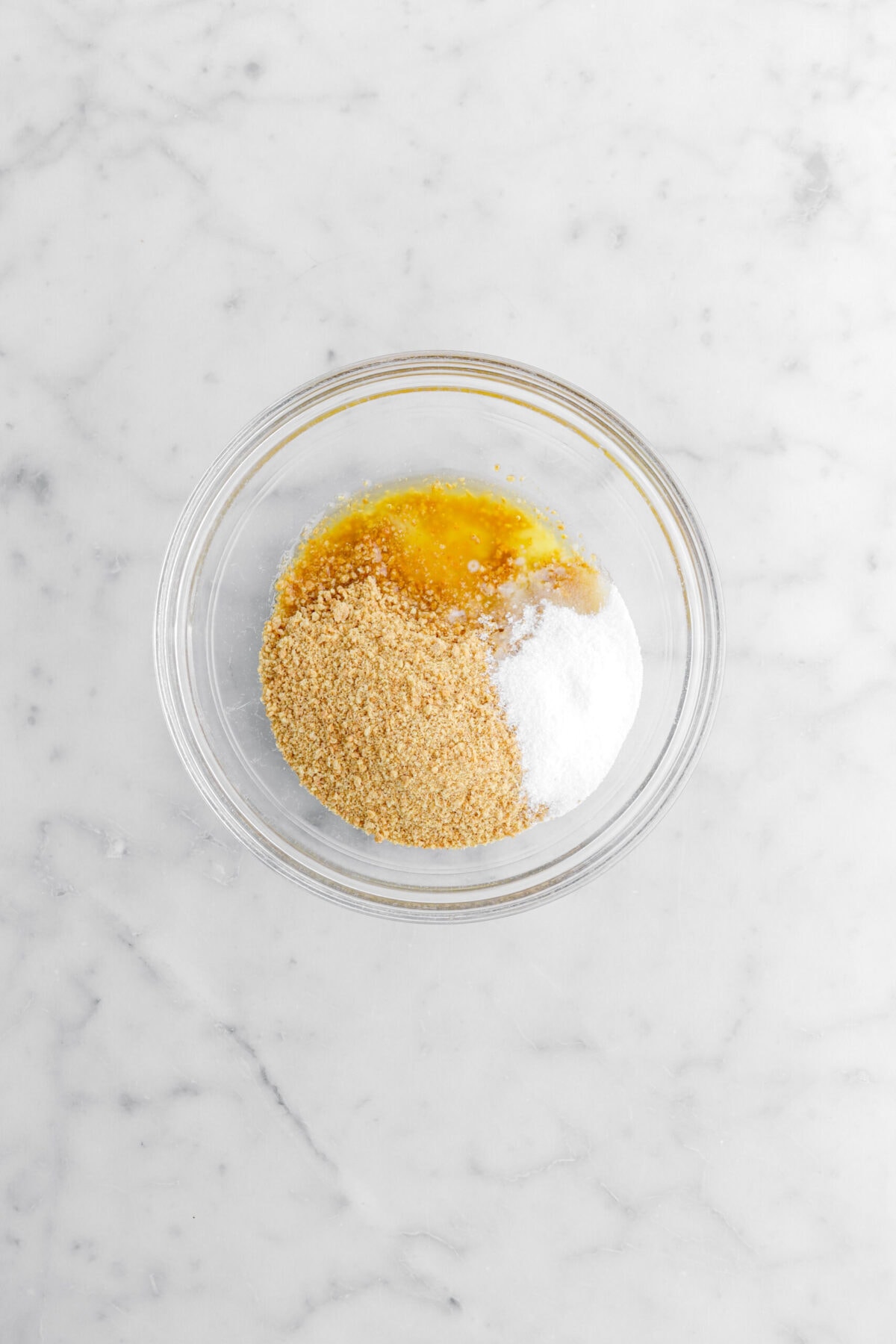 graham cracker crumbs, sugar, and melted butter in glass bowl.