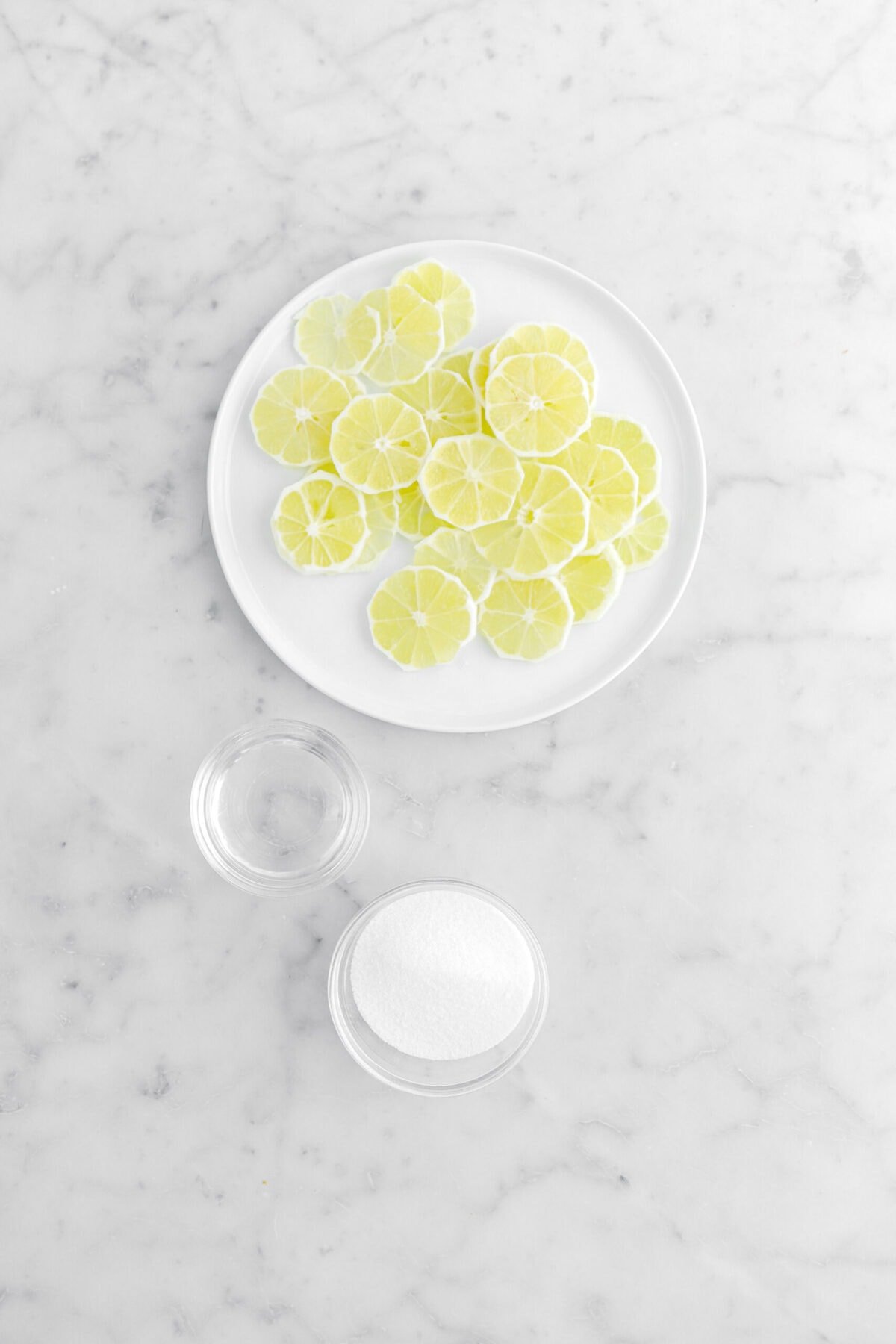 lemon slices, water, and sugar on marble surface.