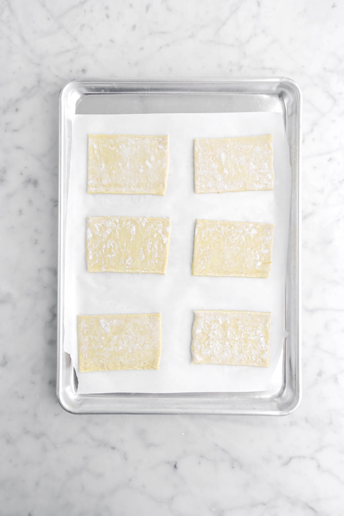 six rectangles of puff pastry on lined sheet pan.