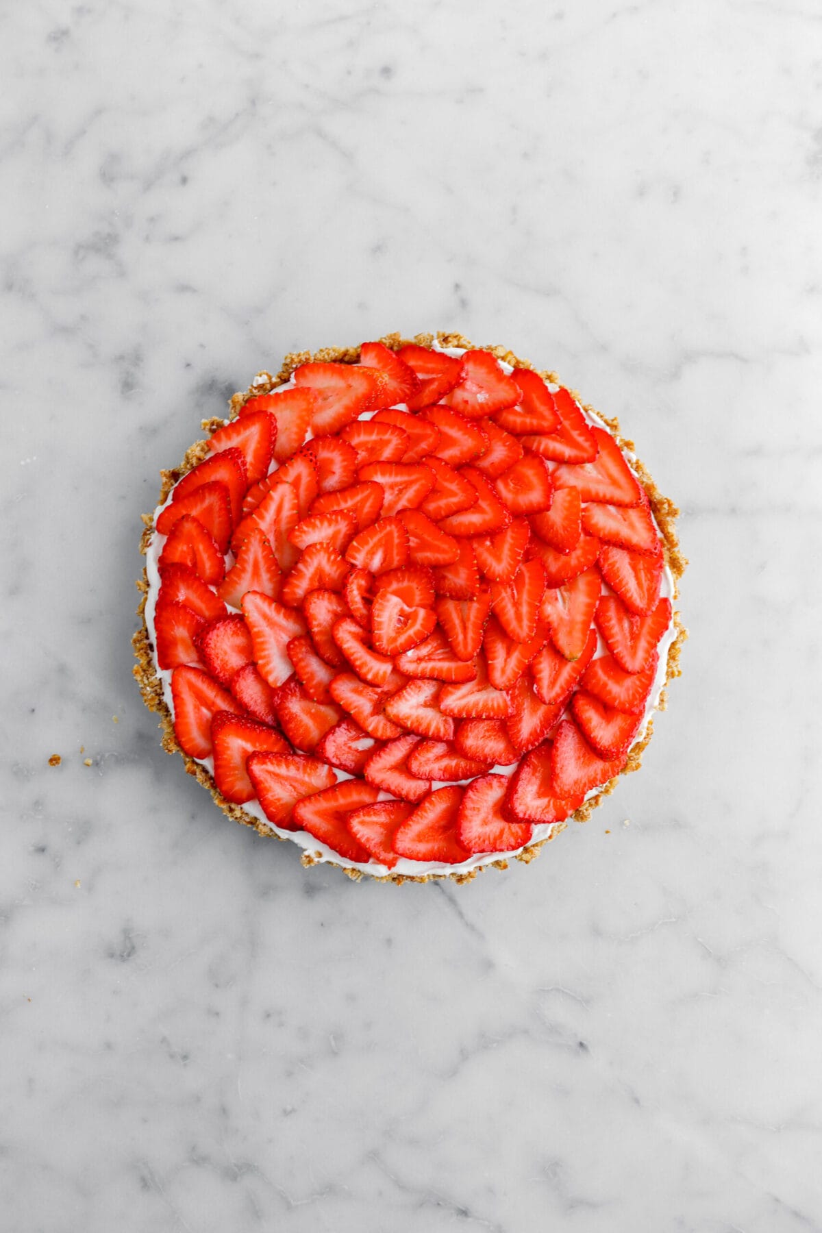 sliced strawberries laid in a circle patter on top of tart.